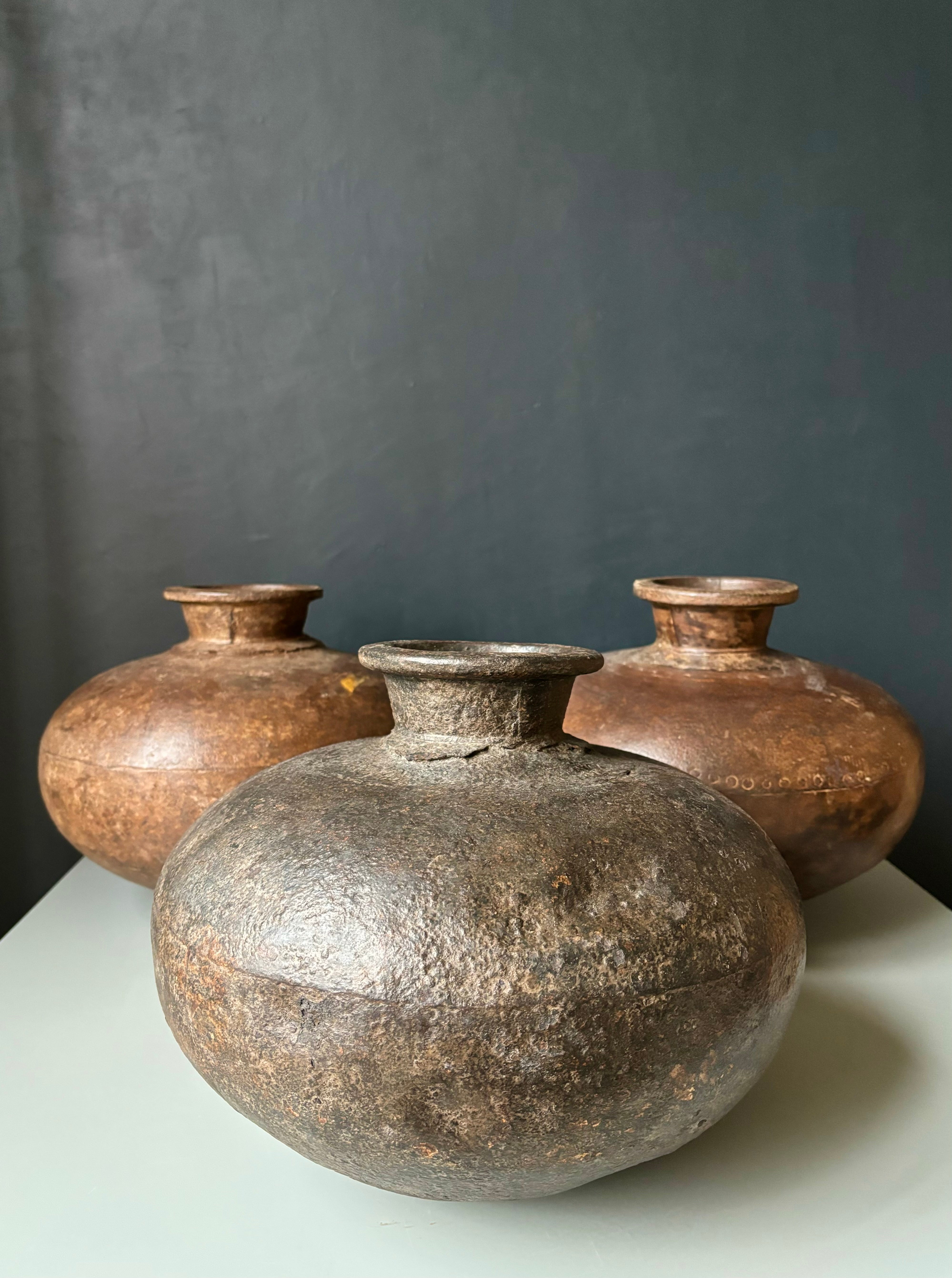 Tre grandi brocche d'acqua rustiche in metallo realizzate a mano da artigiani indiani nel XIX secolo. Ampio ventre generoso e collo svasato su tutti e tre gli articoli. Ottime condizioni vintage con piccole ammaccature dovute all'età. 
Prezzo per