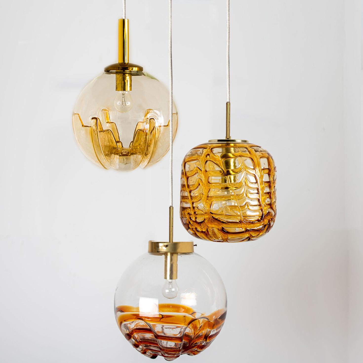 A collection of beautiful and stylish glass pendant lights made in Germany and Italy around the 1960's. The Doria light is made of yellow clear glass in a bubble shape. The Kaiser light is made of clear red-brown glass and the Mazzega light is