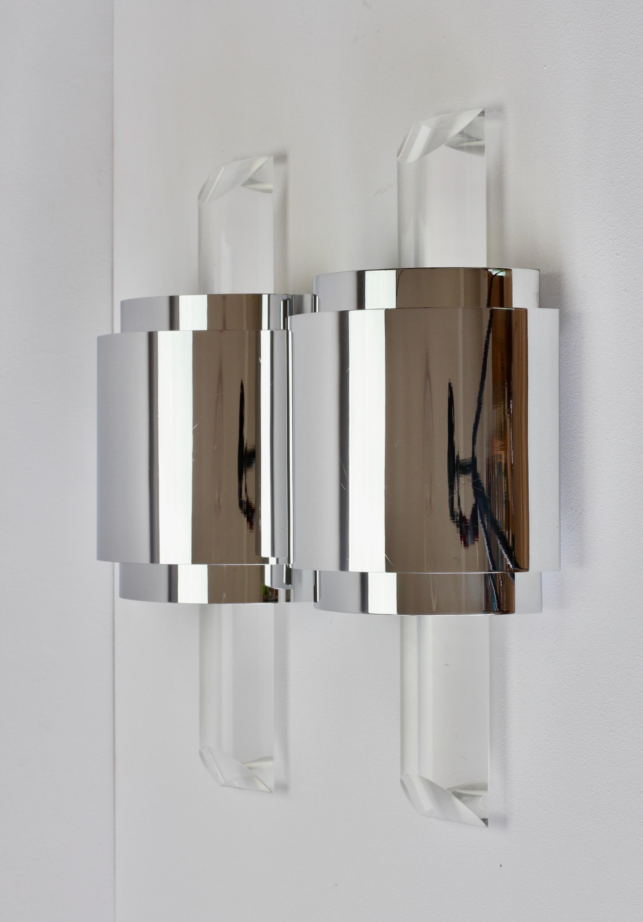 One of a set of four Hollywood Regency style large, oversized cut / angled acrylic / Lucite wall-mounted lamps, lights or sconces in the style of Karl Springer and made in the latter part of the mid-20th century, circa 1975-1985. These illuminate