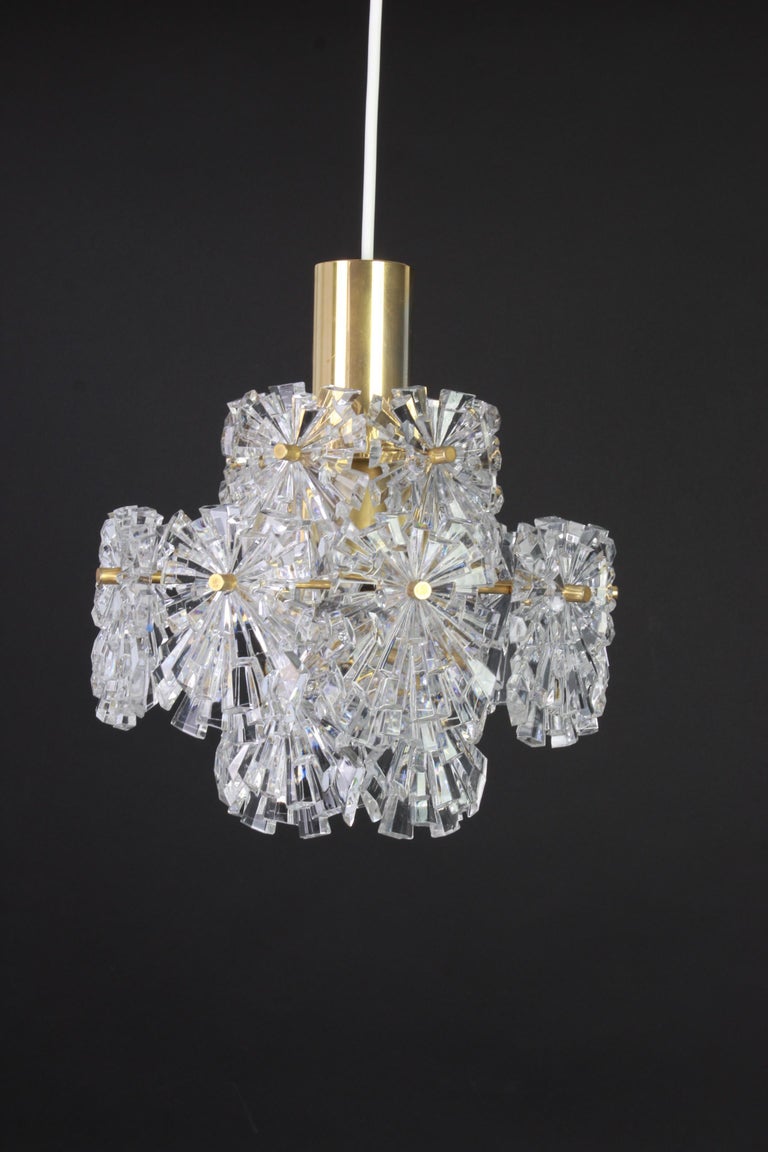 A stunning three-tier chandelier by Kinkeldey, Germany, manufactured in circa 1970-1979. A handmade and high quality piece. The ceiling fixture and the frame are made of brass and have three rings with lots of facetted crystal glass