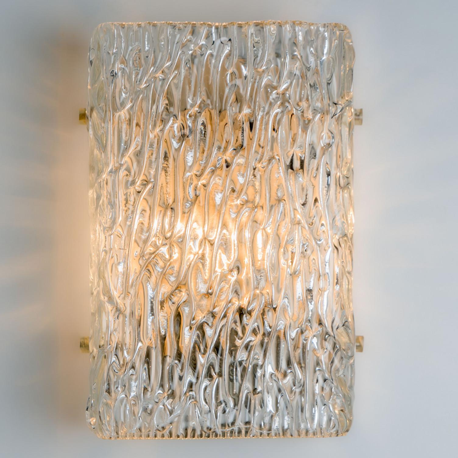 Beautiful high quality light fixture made by Kalmar Leuchten, Austria. Manufactured in mid century, circa 1970 (at the end of 1960s and beginning of 1970s).

This wall light features lights made of handmade wave-textured glass. The sides refract
