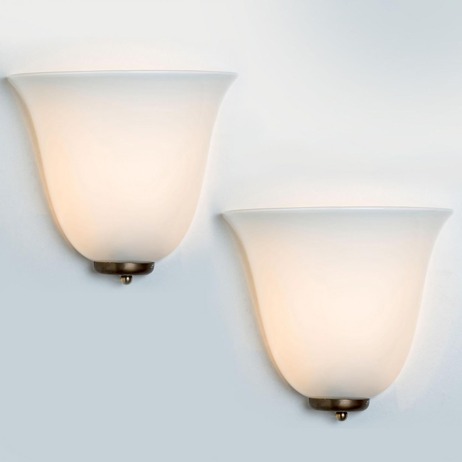 Wonderful hand blown Doria wall lamps. Manufactured in the 1960s. With a beautiful shell of opal glass, and a small brass base.
The stylish elegance of this lamp suits many environments, from mid century to Hollywood Regency, from Danish modern to