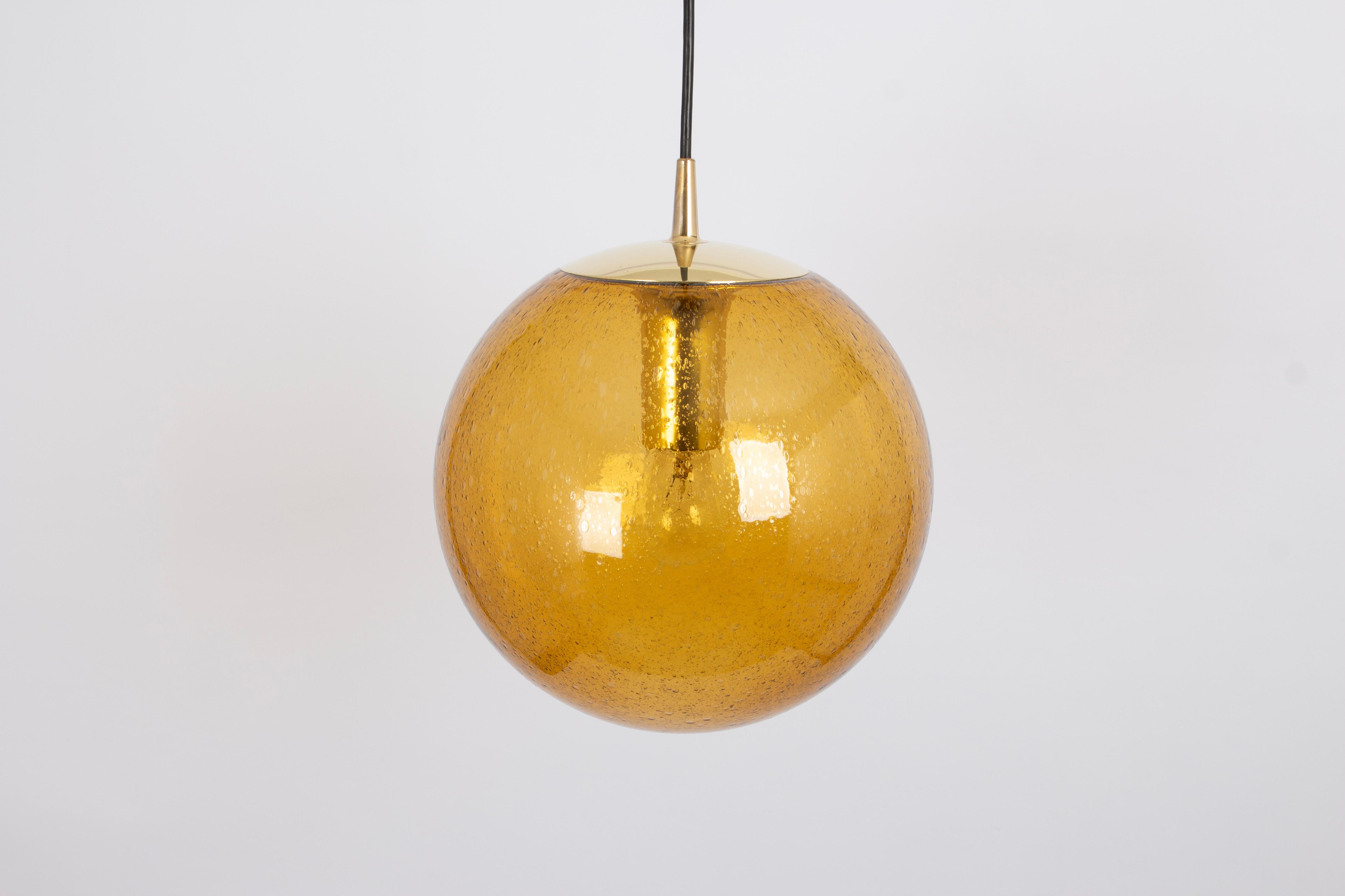 Pendentif rond spécial en verre jaune foncé conçu par Peill & Putzler, fabriqué en Allemagne, vers les années 1970.
De haute qualité et en très bon état. Nettoyé, bien câblé et prêt à l'emploi. 
Chaque luminaire nécessite une ampoule standard E27