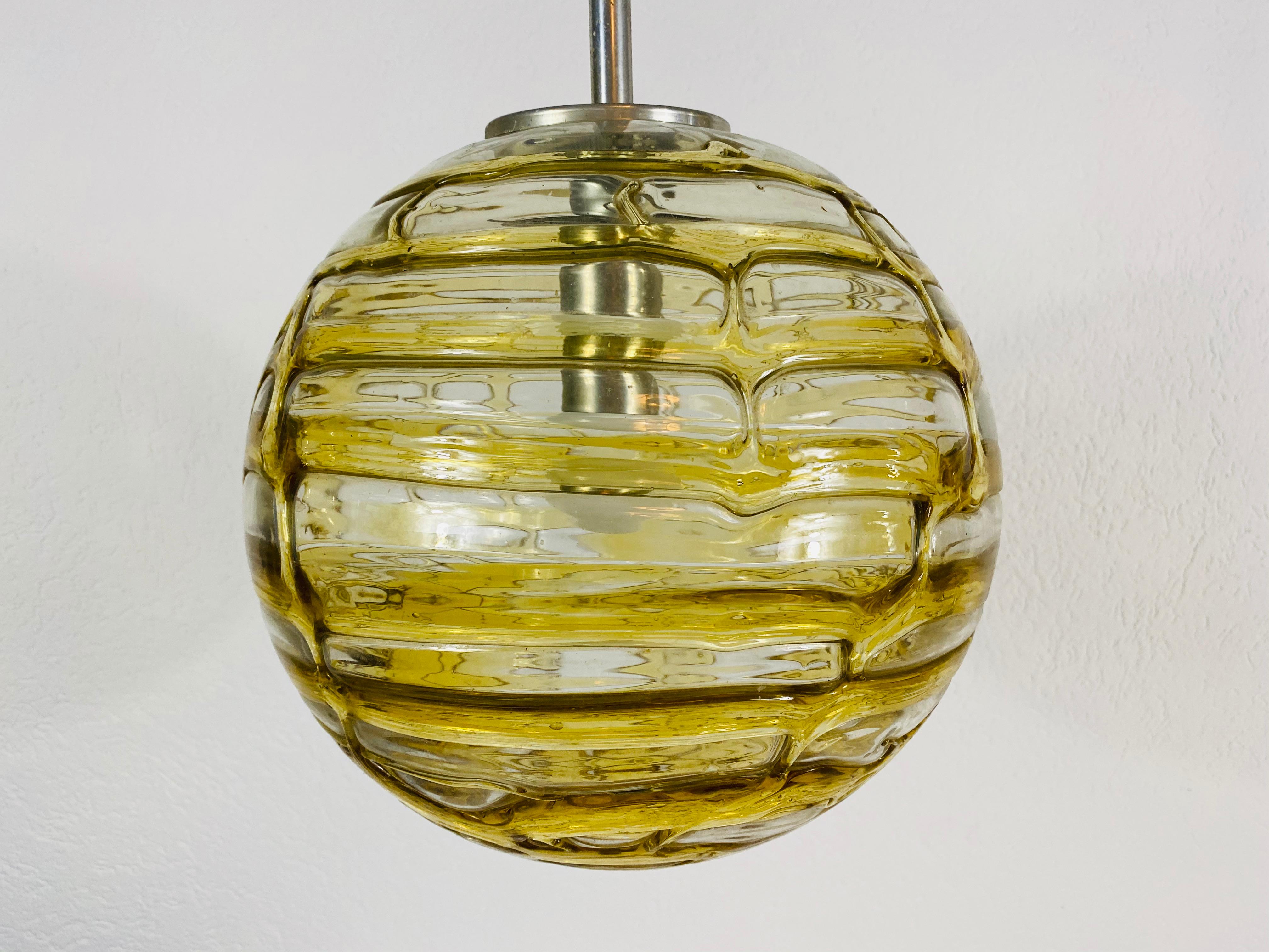 A beautiful glass bowl hanging lamp made in Germany in the 1970s. The light is made of Murano glass. It has an amazing amber color and it is very solid. The glass shape is wave and bubble textured.

The light requires one E27 light bulb. Very good