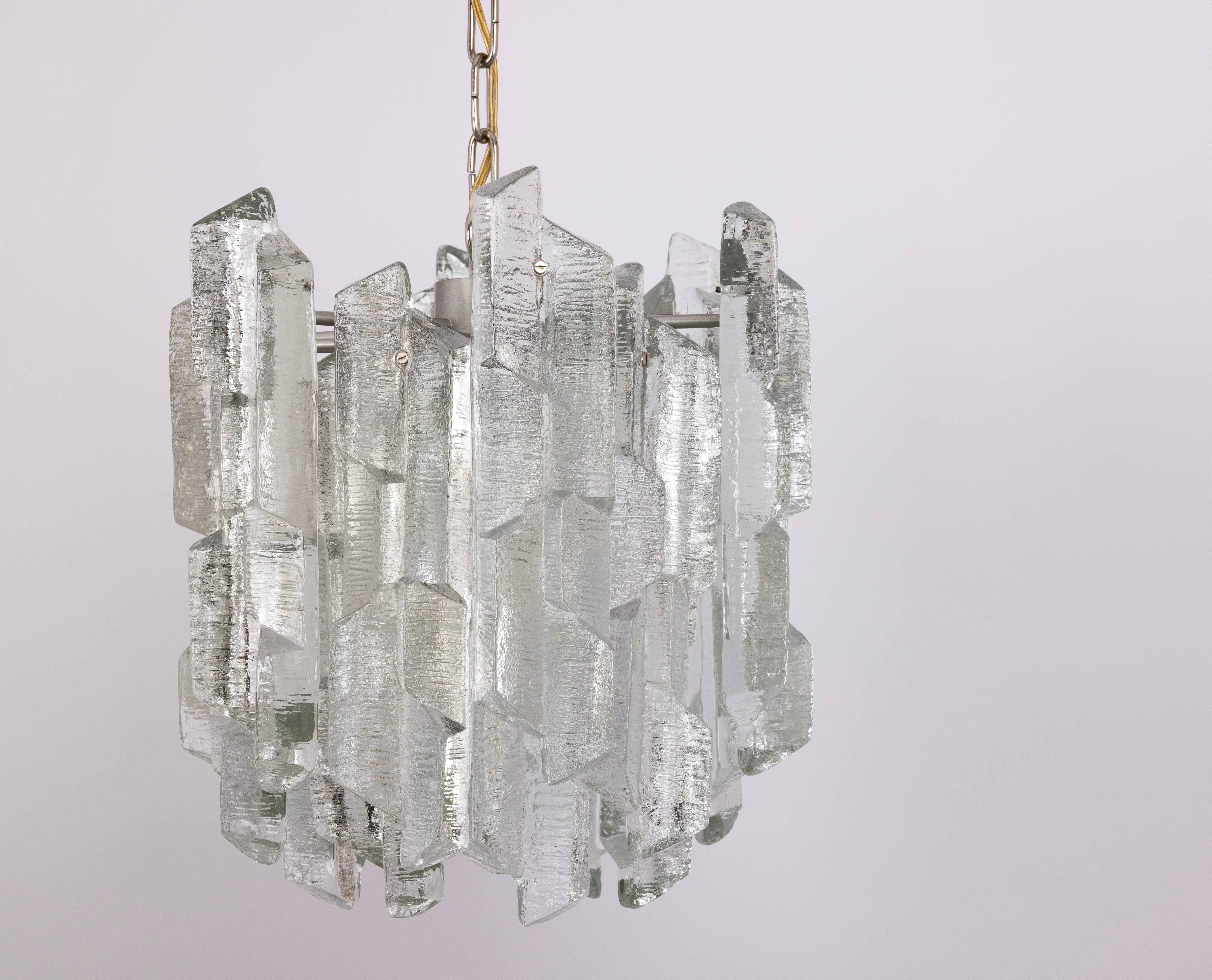 1 of 8  rare and striking chandeliers by Kalmar, model Prisma, produced in the 1970s.
This impressive light features a multi-tiered structure with eighteen structured Murano glass elements that beautifully refract the light, creating a luxurious and