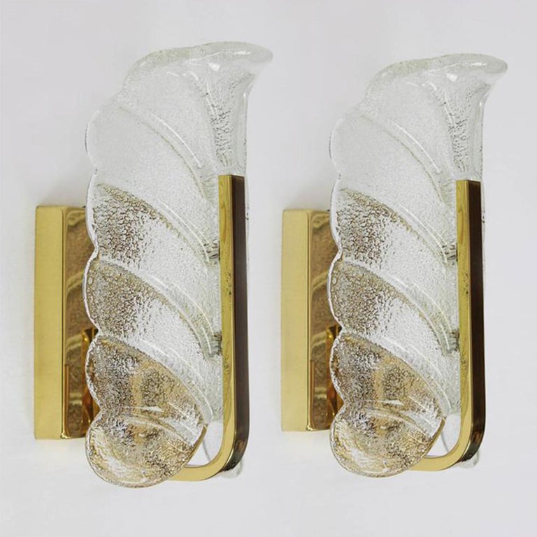 A beautiful large set of high end wall lights with one glass shade and brass frame. The light fixtures are produced in the 1960s by the iconic firm of Orrefors and designed by Carl Fagerlund.

Beautifully carved clear frosted glass shades in a
