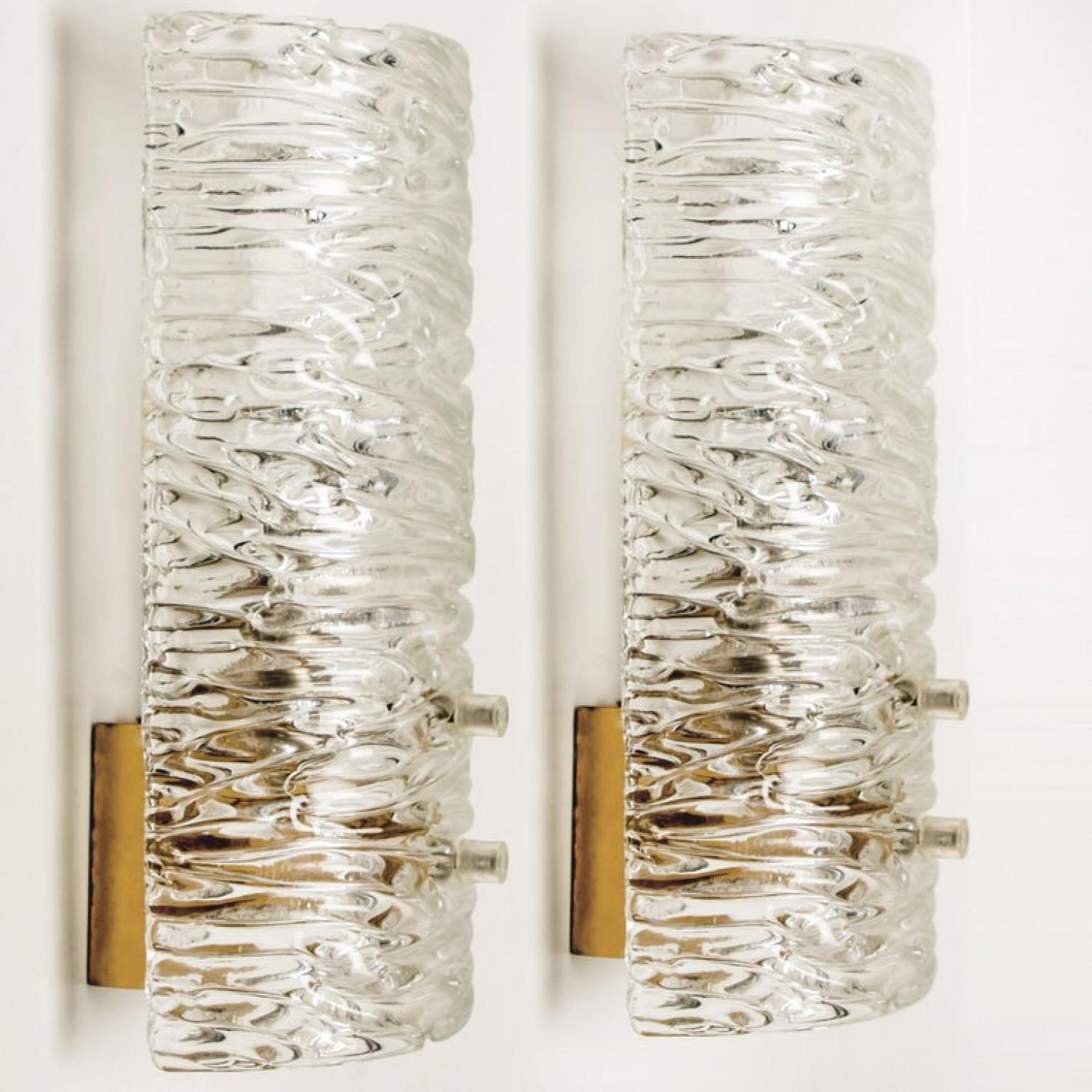 1 of the 12 wall lights by J.T. Kalmar, Vienna, Austria, manufactured in circa 1960. This pair is handmade and high end. Each wall light has a half round wave textured glass shade with a brass back plate,

The wave texture gives a nice diffuse light
