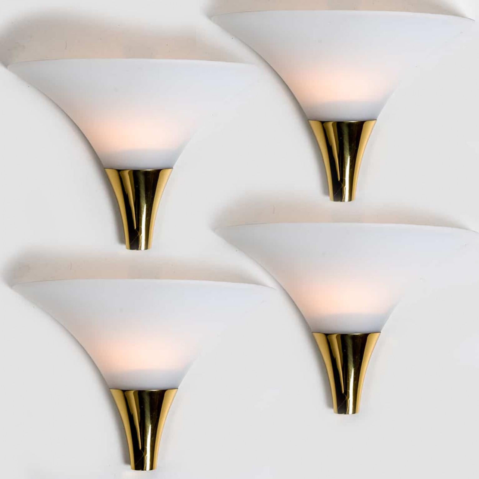 1 of the 16 funnel shaped wall lamps by Glashütte Limburg made in Germany, Europe in the 1970s.
They have a beautiful cone shape and are made of beautiful white, opaque glass and solid brass.
This wall light gives a warm light that suits any