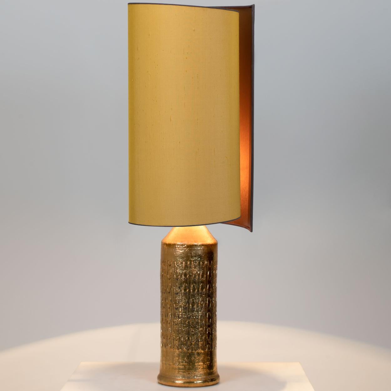 1 of the 2 elegant table lamps. Each lamp features a ceramic base with a rough surface in an off-white glaze with shiny metallic gold glazed patterns, Bitossi, Italy, circa 1960s. With exceptional new custom made silk shades by René Houben. With