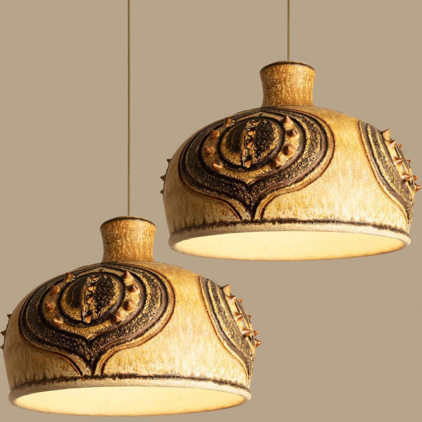 Élégantes lampes suspendues en céramique fabriquées au Danemark. La lampe est fabriquée en céramique ocre, beige et brune et présente un motif avec des pointes en céramique. Illumine magnifiquement.

Une pièce unique dans la pièce.

Nettoyé, bien