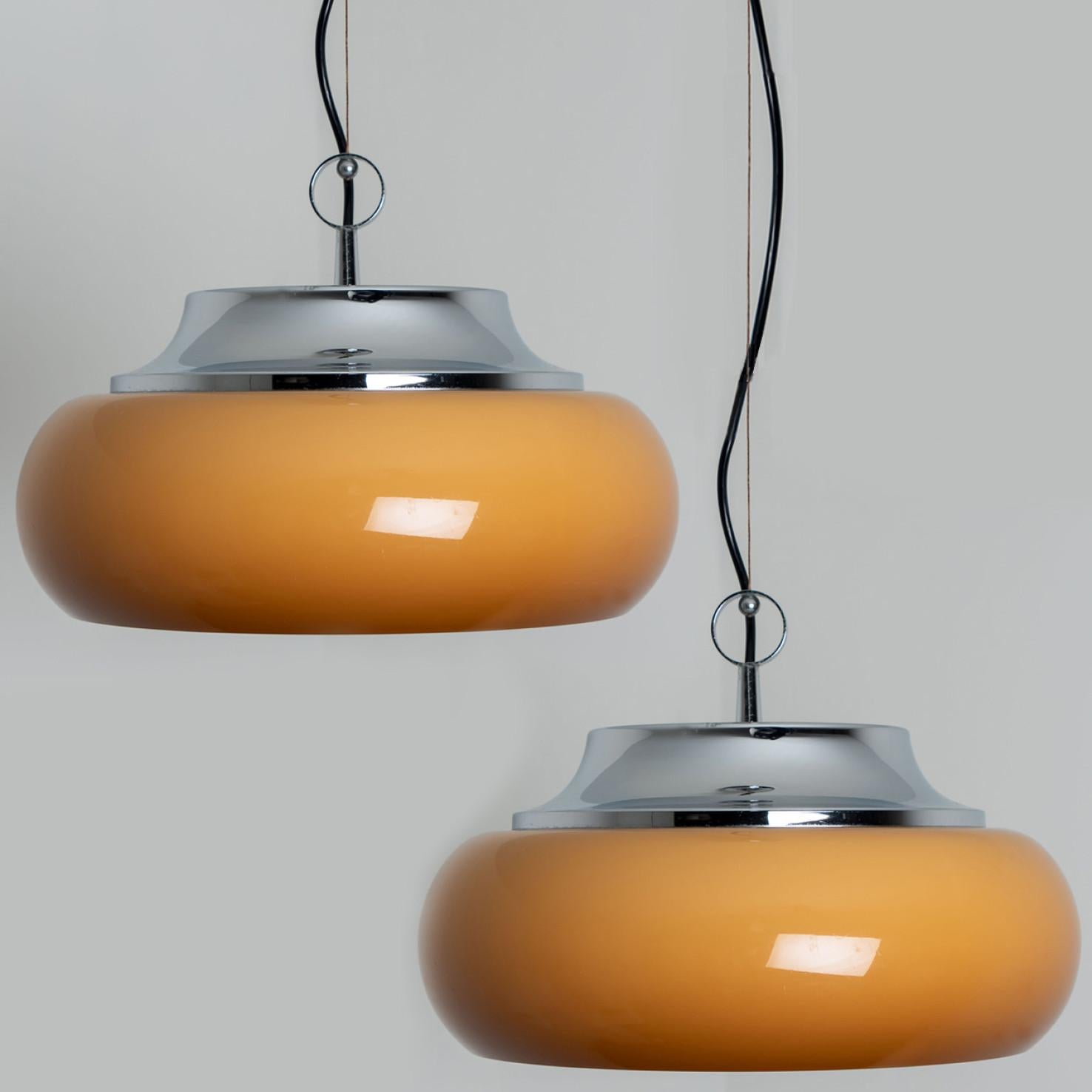 Pair of  beautiful Guzzini pendant lamps made by Meblo Yugoslavia in the 1970s.
A very fun pendant light, in space age  and retro style, because of the use of chrome and brown orange plexi glass.
Because of the orange plexi glass, it's a feast for