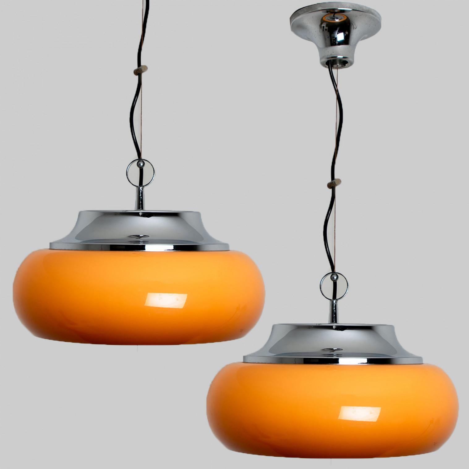 Pair of  beautiful Guzzini pendant lamps made by Meblo Yugoslavia in the 1970s.
A very fun pendant light, in space age  and retro style, because of the use of chrome and brown orange plexi glass.
Because of the orange plexi glass, it's a feast for