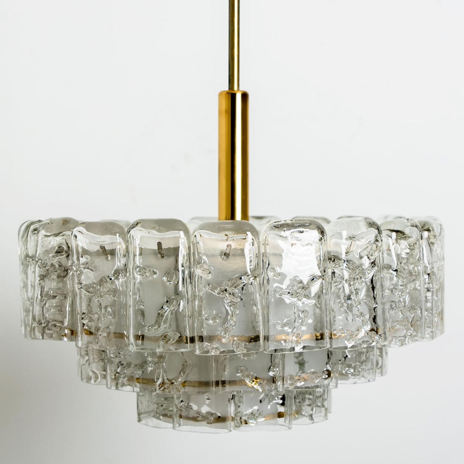 Fantastico lampadario a tre livelli della metà del secolo scorso di Doria Leuchten Germany. Prodotto intorno al 1960.
Tre anelli di cilindri in vetro di Murano sospesi da un apparecchio con dettagli in ottone. Di qualità pesante e in ottime