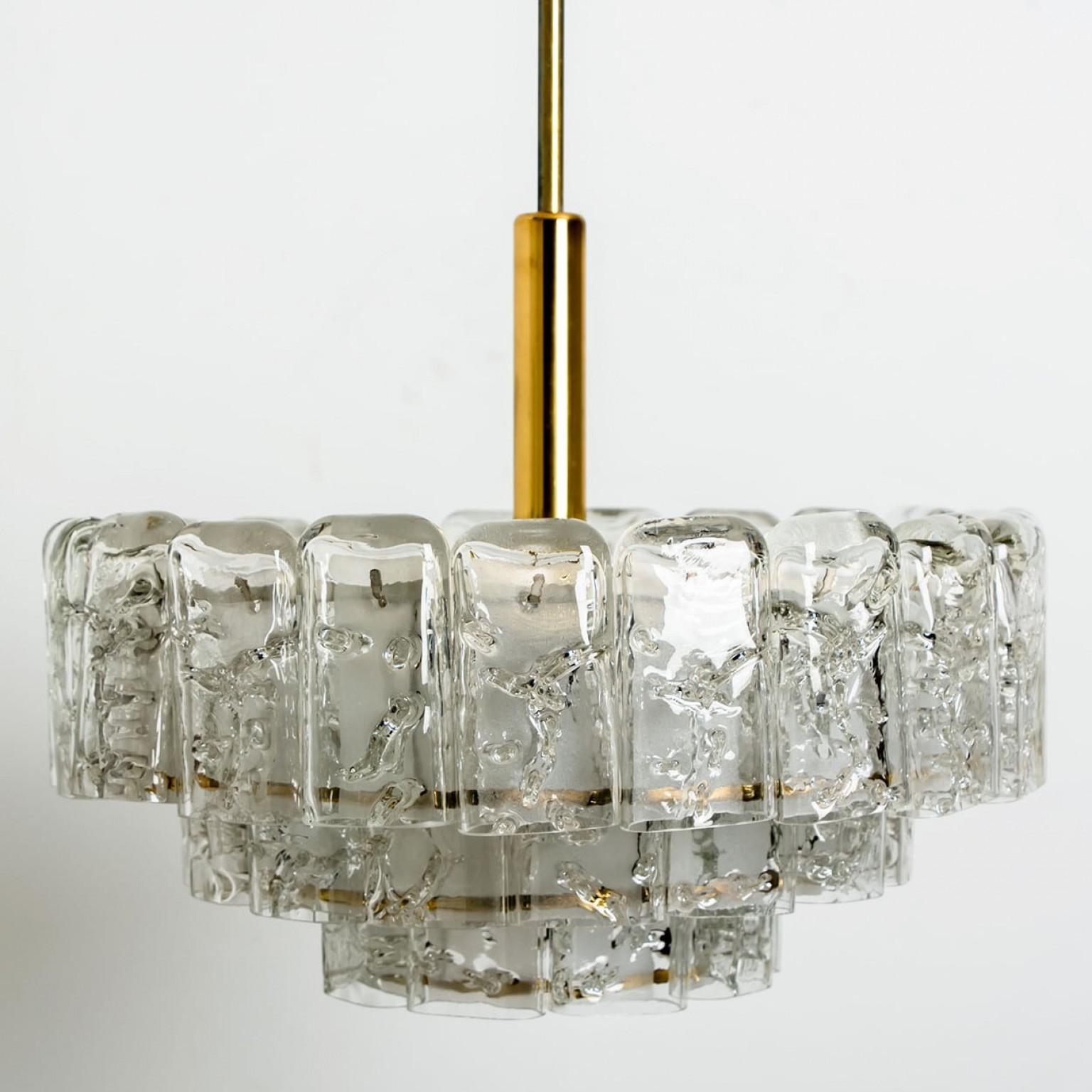 Fantastique lustre à trois niveaux de Doria Leuchten Allemagne. Fabriqué vers 1960.
Trois anneaux de cylindres en verre de Murano suspendus à un luminaire avec des détails en laiton. De grande qualité et en très bon état. 

Nettoyé, bien câblé et
