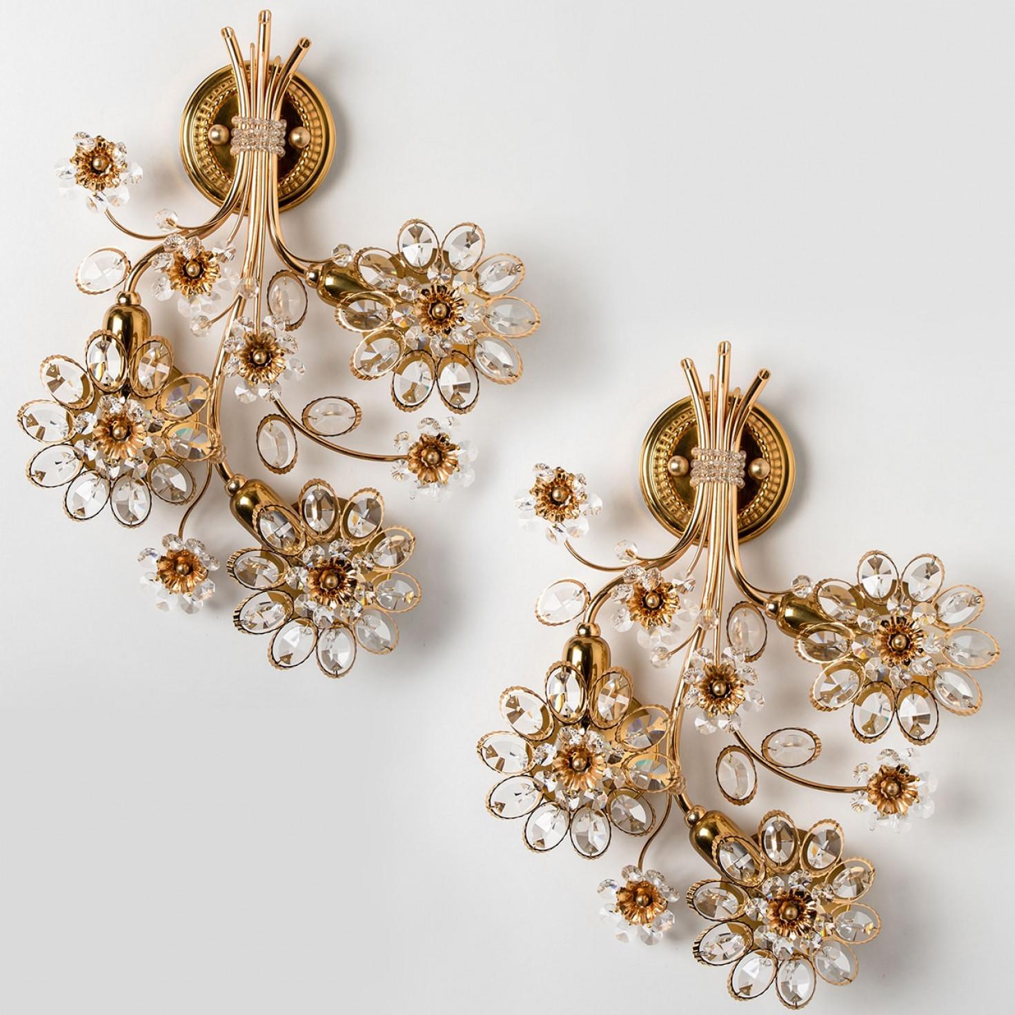 Impresionante candelabro de pared dorado y cristal de Palwa, Alemania. Fabricado alrededor de 1965-1975.
Este lujoso aplique de pared presenta cristales bellamente tallados en forma de flores y pétalos sobre un marco de latón chapado en