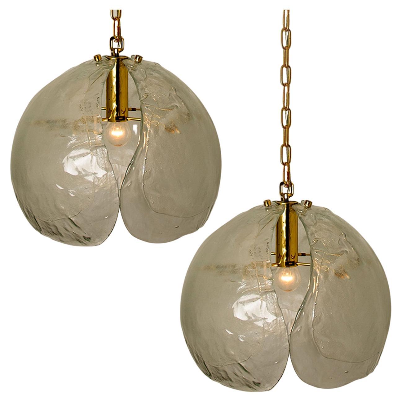 A nice pair of pendant lights in the style of Kalmar. Three clear murano glasses are mounted on a brass fixture.
The hand blown leaves are refracting the light in a beautiful way. It fills the room with a soft and welcoming glow.

Measures: