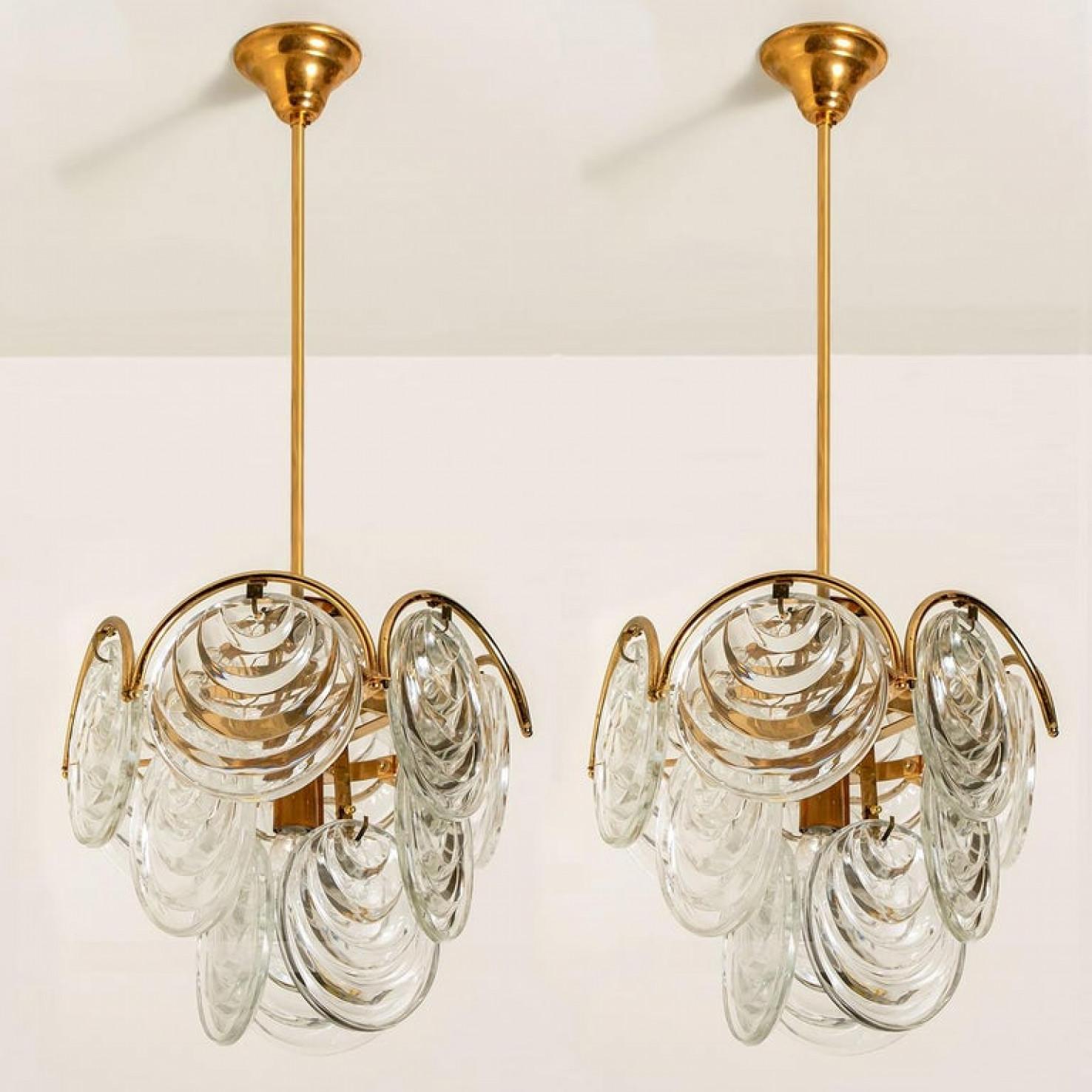 Questi lampadari scultorei con un design di lastre di vetro rotonde e strutturate sono stati prodotti nella metà del secolo scorso, intorno al 1970 (fine anni '60 o inizio anni '70).
L'apparecchio ha diversi paralumi in vetro. Ogni paralume in vetro