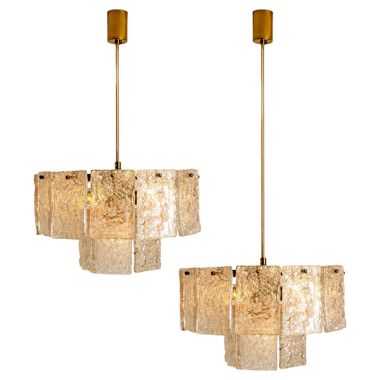 These sculptural chandeliers with a design of textured rectangular glass plates are from the historical lighting company Hillebrand,. Manufactured in mid century, circa 1970 (late 1960s or early 1970s).

The fixture has 18 glass shades. Each clear