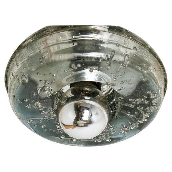 1 der 2 Doria-Leuchten sind aus dickem mundgeblasenem Glas auf einer quadratischen silberfarbenen Rückwand gefertigt. Das Glas erzeugt einen schönen Lichteffekt an der Decke, auf dem Tisch oder an der Wand. Jede Lampe hat eine E14-Fassung (max. 30