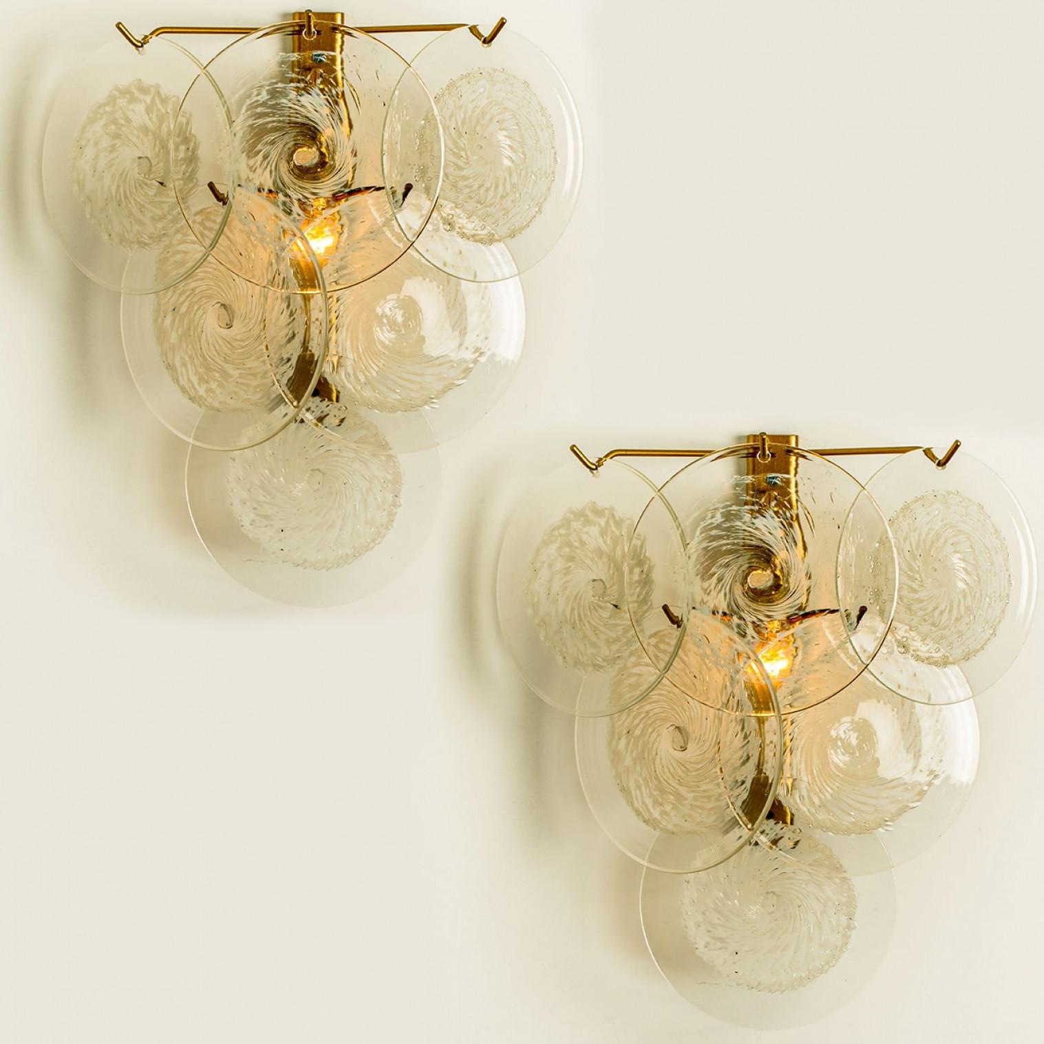 Une magnifique applique murale, attribuée à Vistosi, Italie, fabriquée vers 1960. Chaque lampe comporte six disques de verre clair de Murano avec un tourbillon blanc au milieu. Les appliques sont complètes - il ne manque ni crochet ni disque de