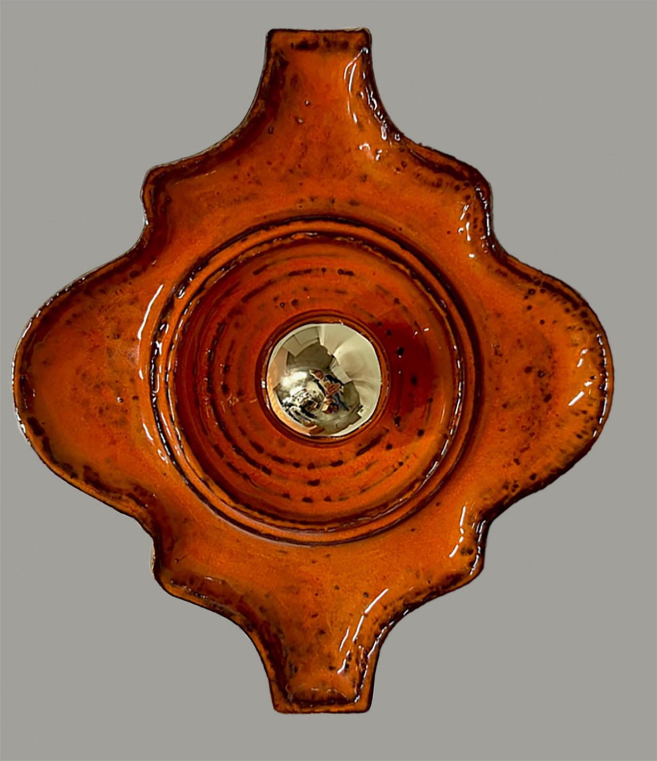 Playful orange ceramic wall light in Manufactured in Germany in the 1970s.

The style of the glaze is called 'Fat Lava'. Which means the glaze is thick on some parts, like lava.
A typical way to finish ceramic in mid-century West-Germany,