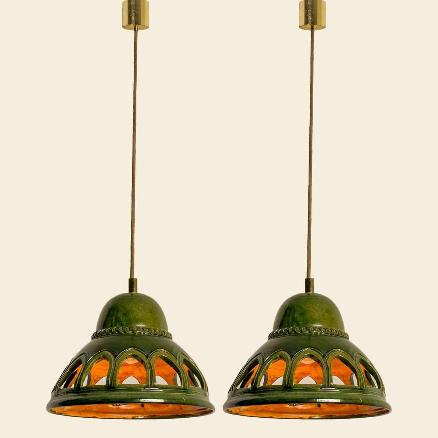 Stylish ceramic pendant lights made in West-Germany around 1970's. The lights are made of green glazed ceramic and have 12 holes in it. The pendant is glazed in 'Fat Lava' style. The green ceramic fits beautifully with warm, gold or clear light