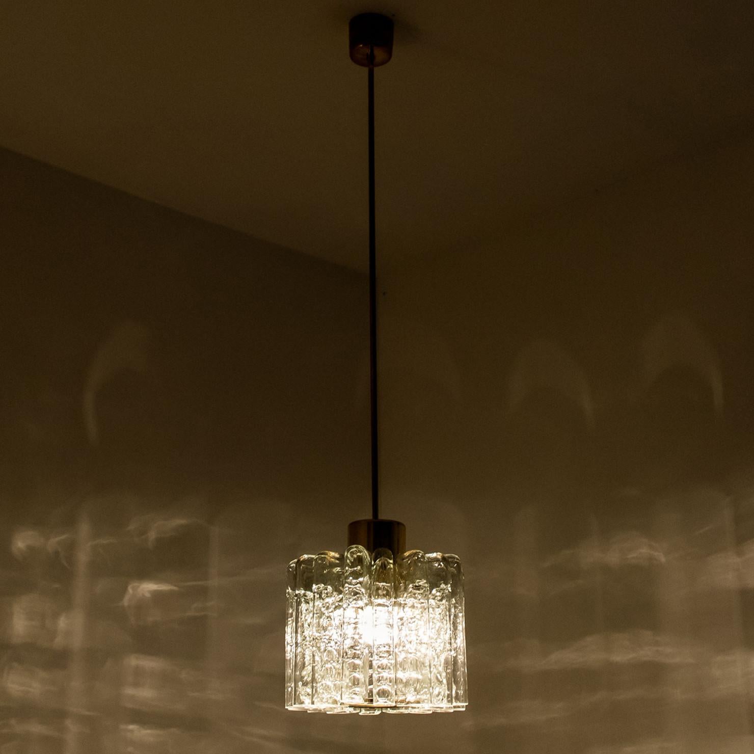 Tulip shaped glass pendant light, manufactured by Doria Leuchten Germany in circa 1960.

This handmade pendant consists of a brass rod with an array of textured round tube-shaped glass rods. Due the combination of materials, opal and clear glass,