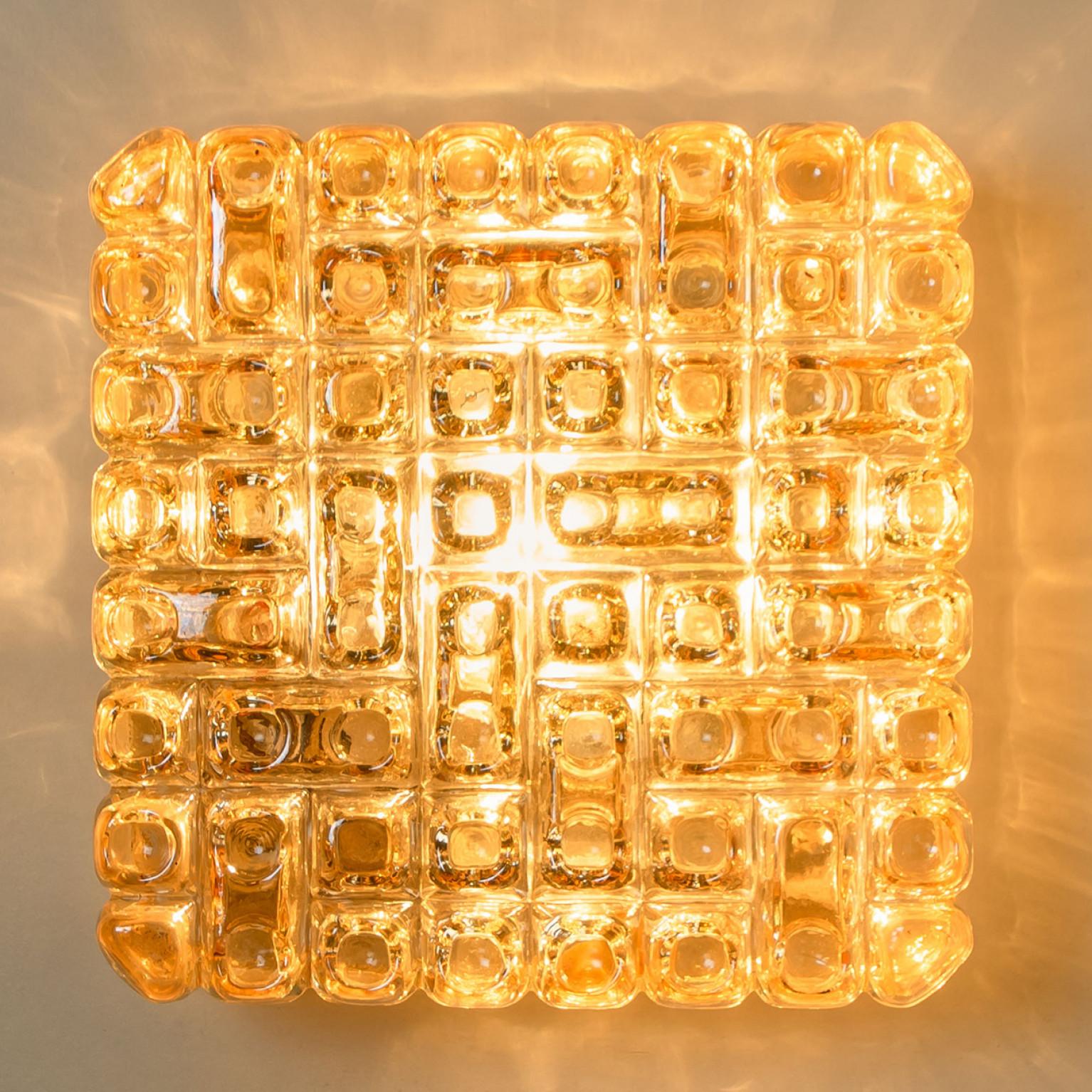 Square shaped wall lights in bubble textured glass with gold details. Manufactured in Germany during the 1960s. ERCO is a leading international specialist in architectural lighting. The 1934 established family business now operates as a global