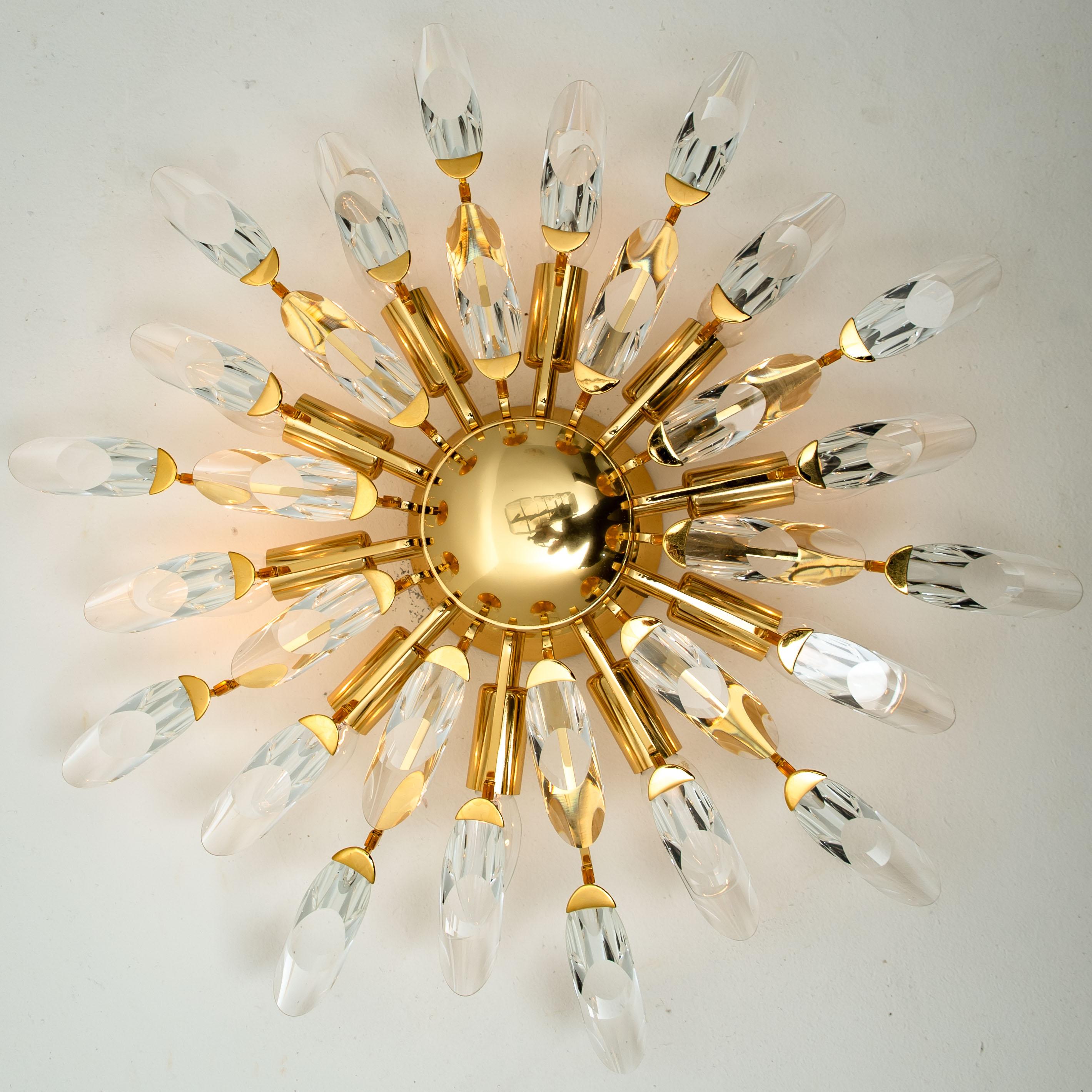 High-end gilded brass flushmount by Stilkronen, made in Italy, circa 1975, featuring a sunburst array of branches holding 30 clear crystals pieces. The crystals refract light beautifully and are perfect for a soft, warm and welcoming glow in the
