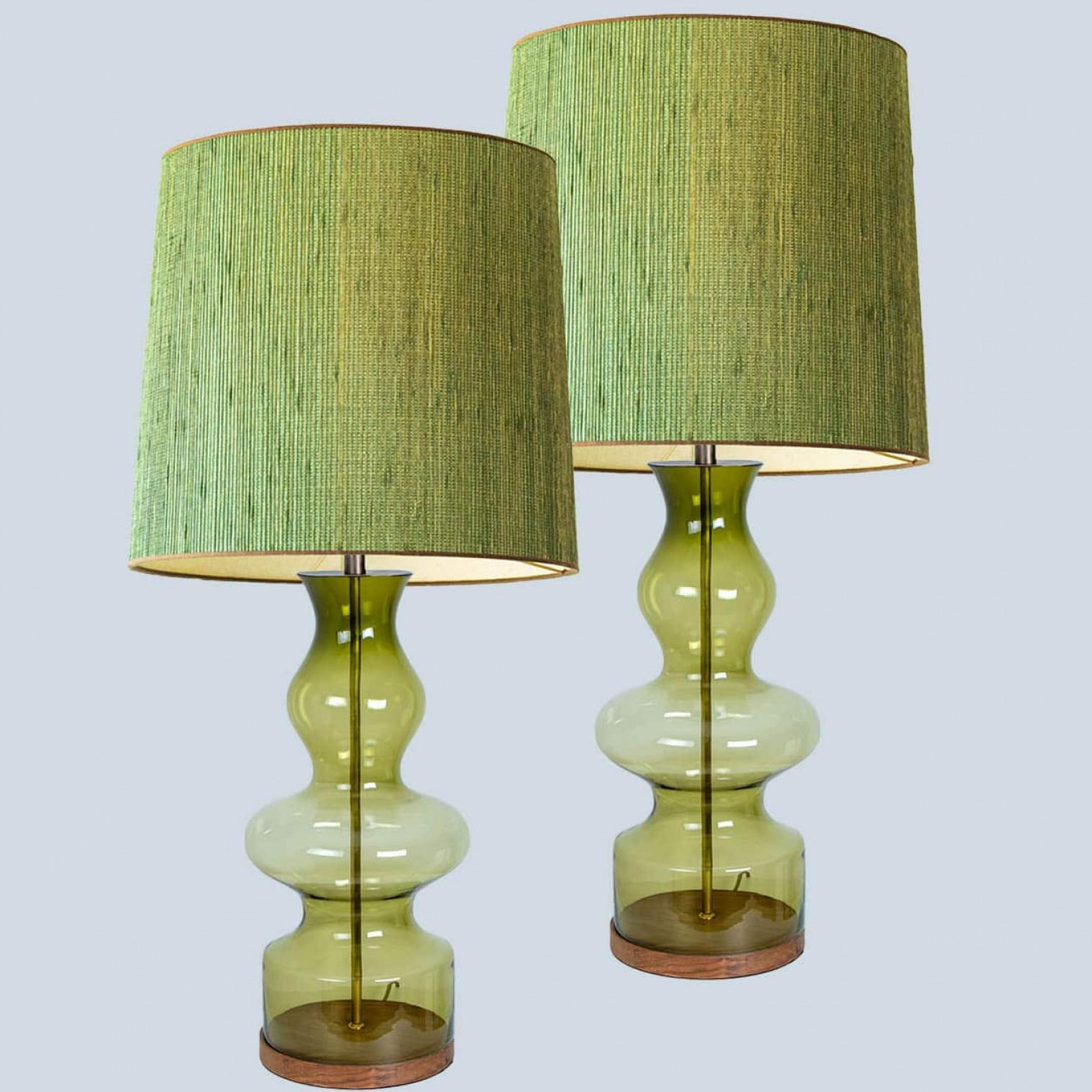 Un design unique, minimaliste et intemporel. Chaque lampe de table en verre extra large présente une base de forme transparente exceptionnelle verte avec un pied en bois de noyer massif avec des accents en laiton ancien et une tige en laiton qui