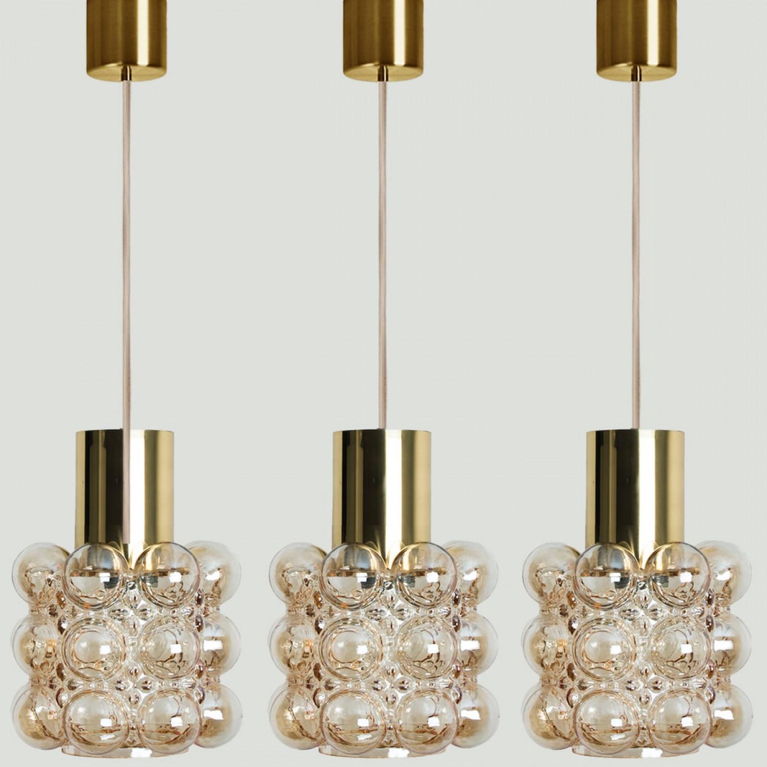 1 of the 3 beautiful bubble glass pendant lights designed by Helena Tynell for Glashütte Limburg, 1960. A classic design with brass details and beige cord, the hand blown amber glass gives a wonderful glow.

Helena Tynell is a finish glass and