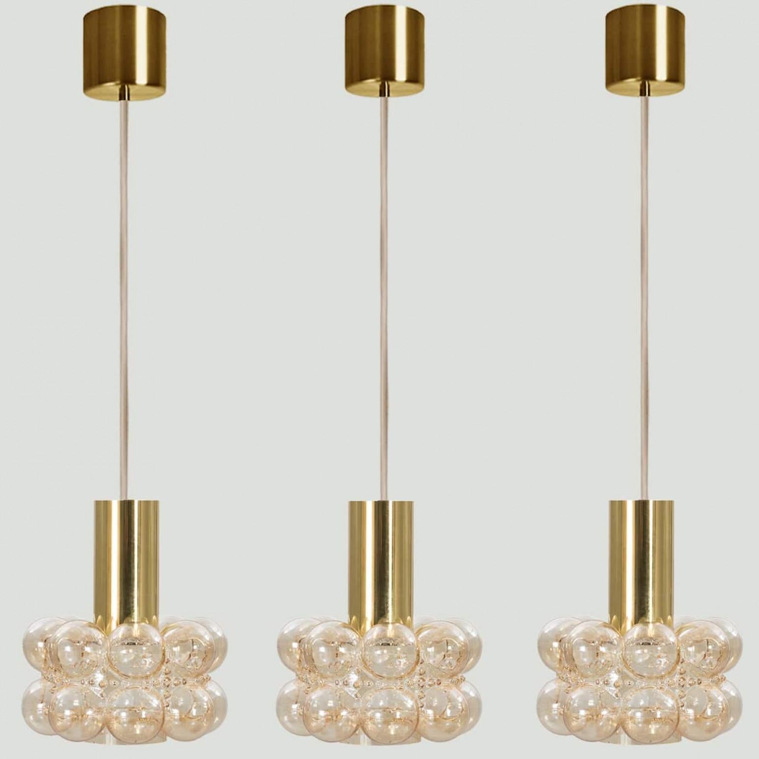 Plusieurs magnifiques lampes suspendues en verre bullé conçues par Helena Tynell pour Glashütte Limburg, 1960. Un design classique avec des détails chromés, le verre ambré soufflé à la main donne une merveilleuse lueur.

Helena Tynell est une
