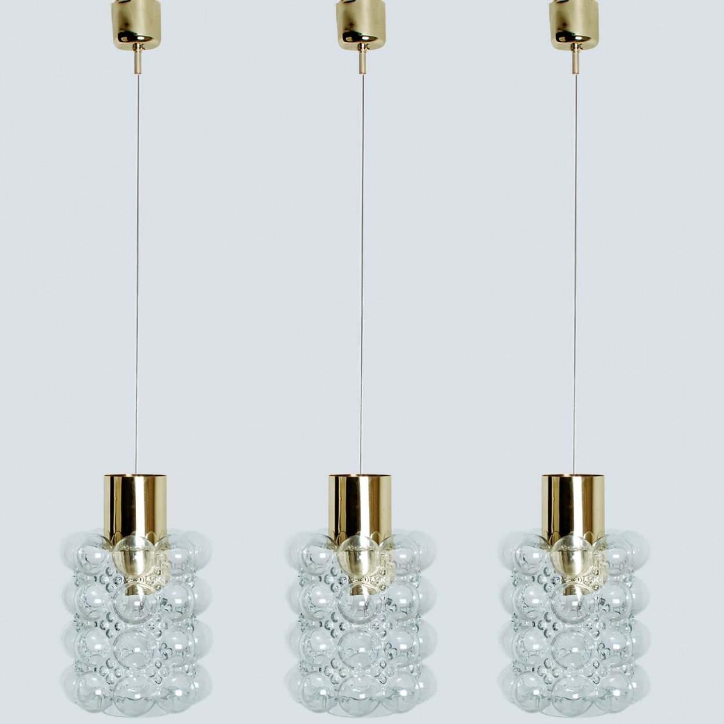 1 der 3 schönen Pendelleuchten aus Blasenglas, entworfen von Helena Tynell für Glashütte Limburg, 1960. Ein klassisches Design mit messingfarbenen Details, das mundgeblasene Glas leuchtet wunderbar.

Helena Tynell ist eine Designerin für Glas und