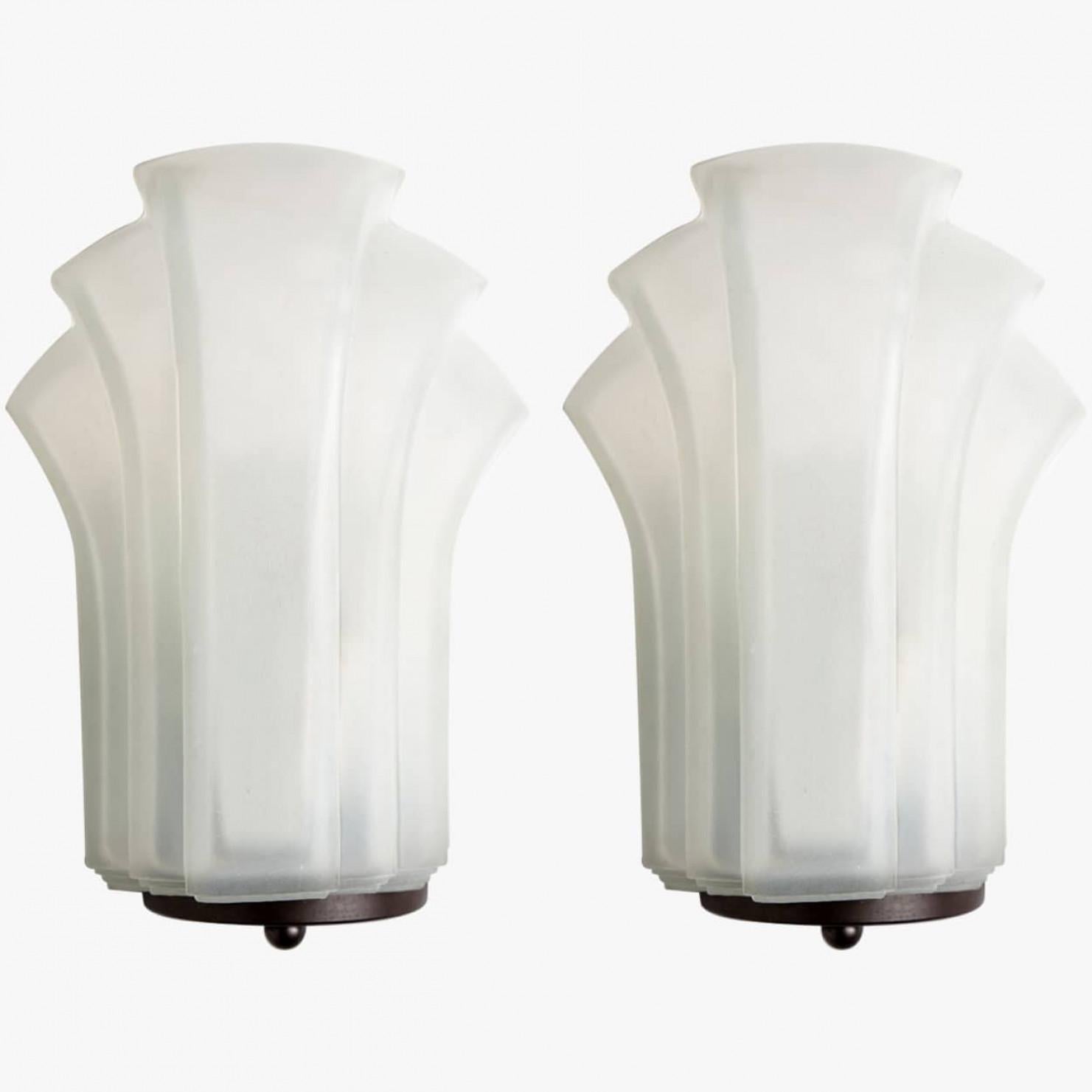 1 de los 4 pares de apliques de cristal de leche de estilo Art Déco. Fabricado en Alemania hacia 1970.
Las luces tienen forma de concha, en líneas típicas del art déco. Serían una adición ganadora a cualquier estilo de interior, desde el moderno