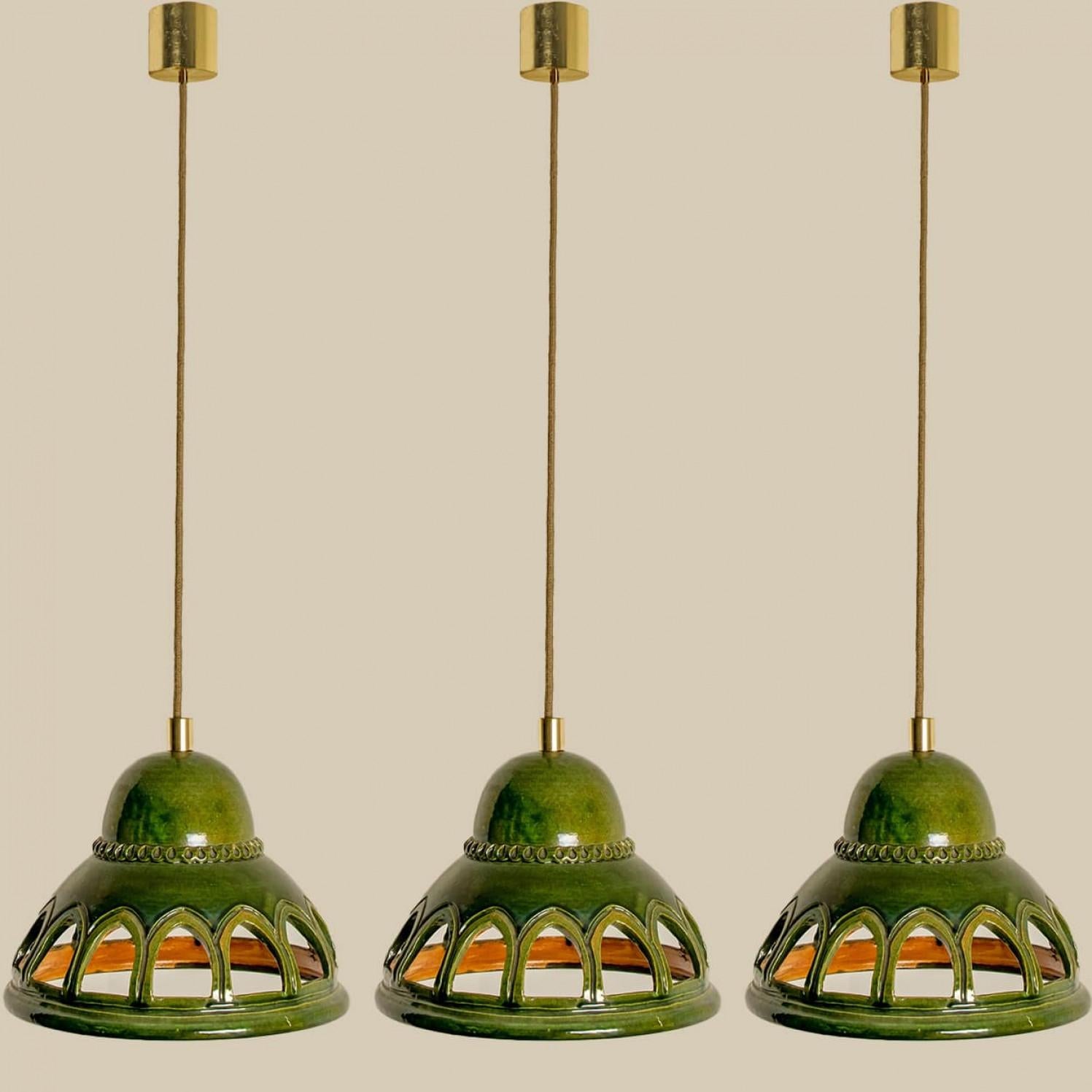 Stylish ceramic pendant lights made in West-Germany around 1970's. The lights are made of green glazed ceramic and have 14 holes in it. The pendant is glazed in 'Fat Lava' style. The green ceramic fits beautifully with warm, gold or clear light