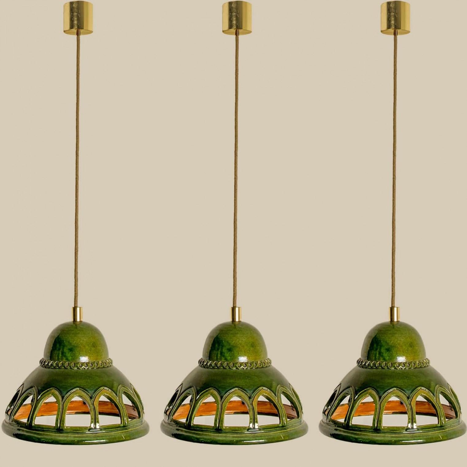 Eleganti lampade a sospensione in ceramica realizzate nella Germania occidentale intorno agli anni '70. Le luci sono realizzate in ceramica smaltata verde e presentano 14 fori. Il ciondolo è smaltato in stile 