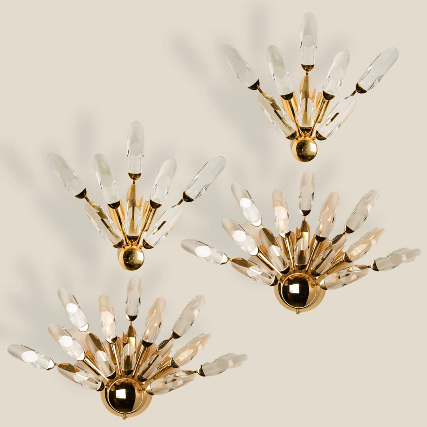 1 of the 4 high-end gilded brass wall lights by Stilkronen, made in Italy, circa 1975.

Each fixture is featuring a half sunburst array of branches holding 8 or 14 clear crystals pieces.

The crystals refract light beautifully and are perfect for a