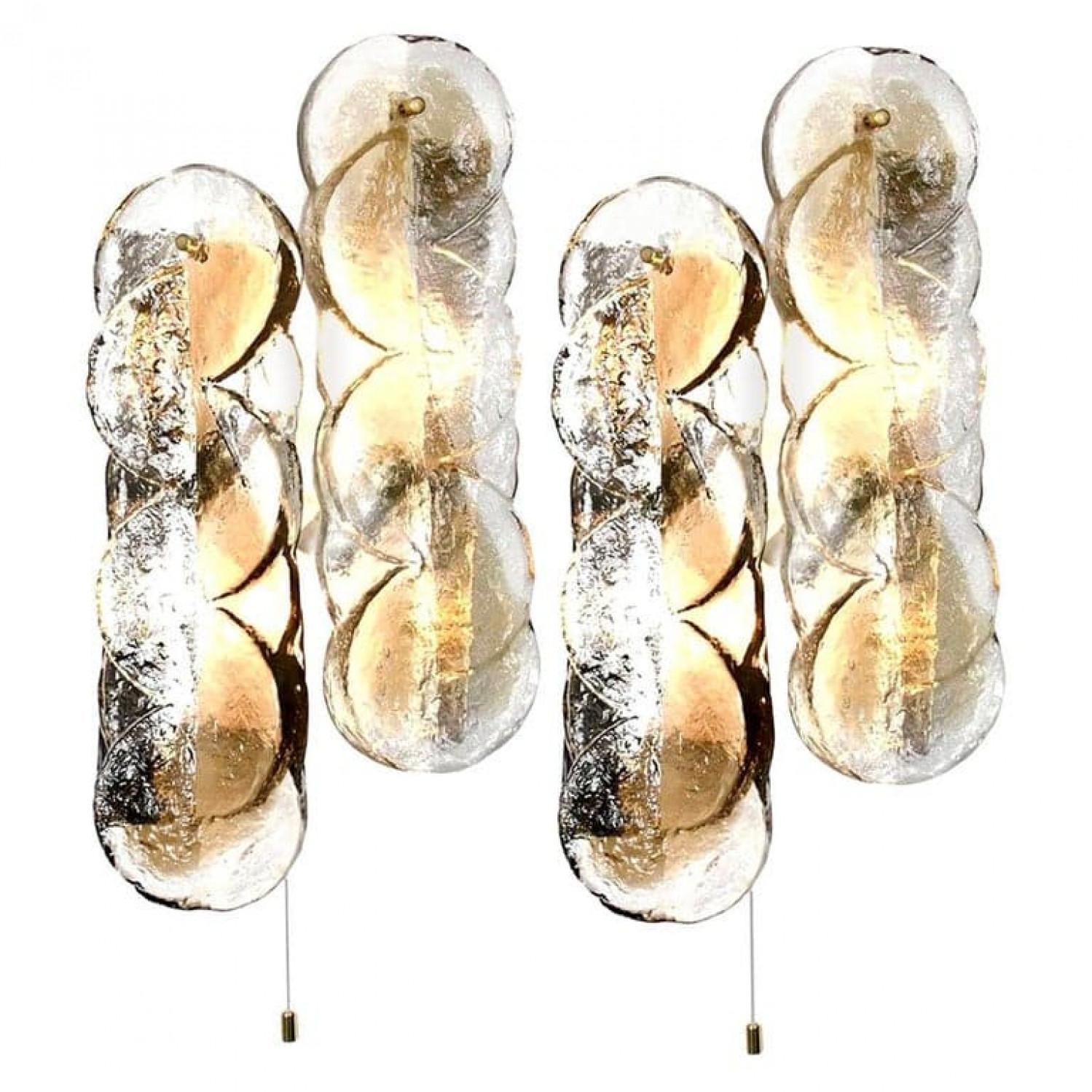 1 de los 4 apliques Kalmar en forma de remolino con paneles de cristal transparente con raya de color ámbar dorado claro en él. El hermoso cristal de textura gruesa se complementa con los herrajes de metal blanco. Bonitos pomos de latón.

Tenga en