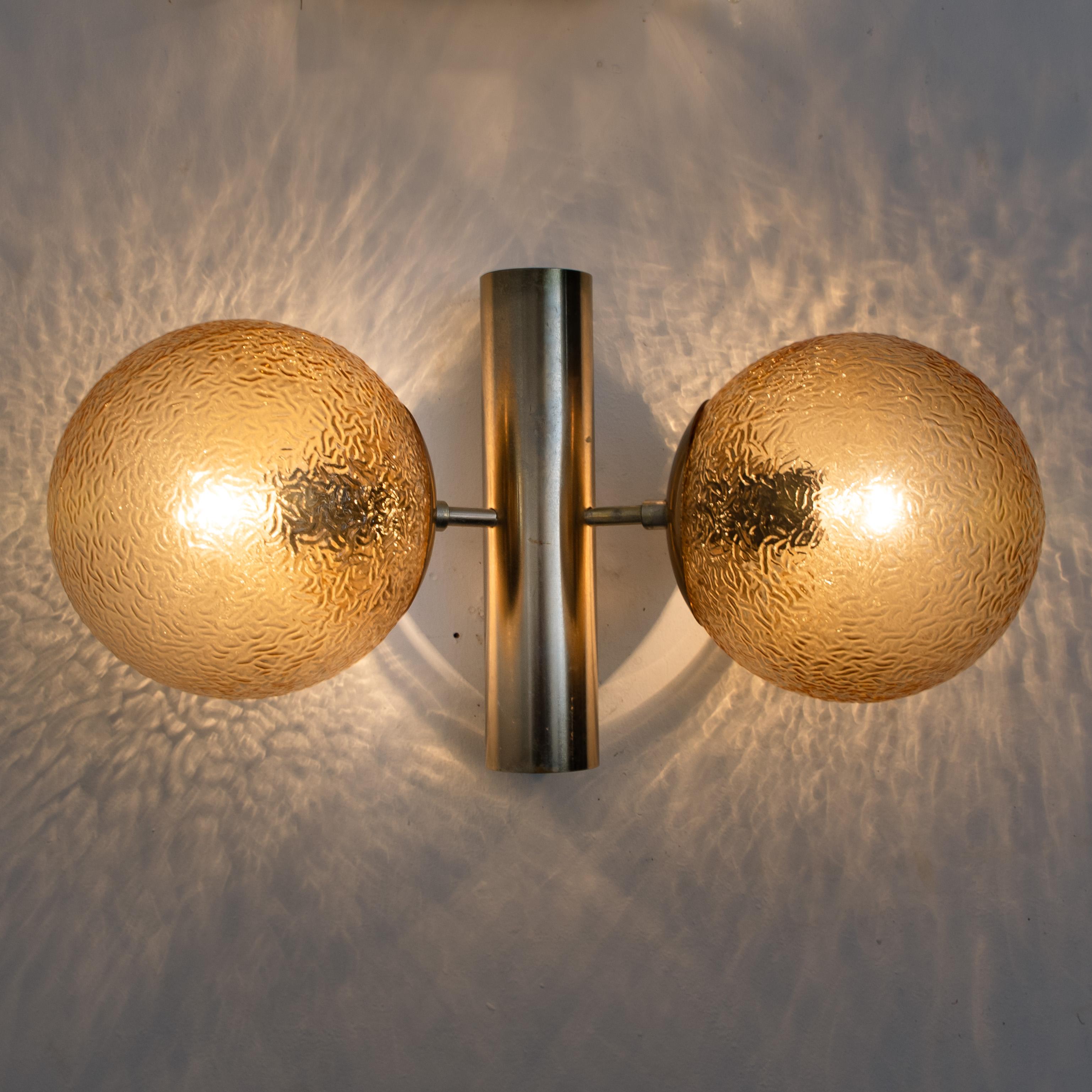 Four gorgeous wall lights with a molecular structure brass central body is surround by 2 attached globes. With amber colored glass. Illuminates beautifully. 

Measures: Height of the wall lights (10.2