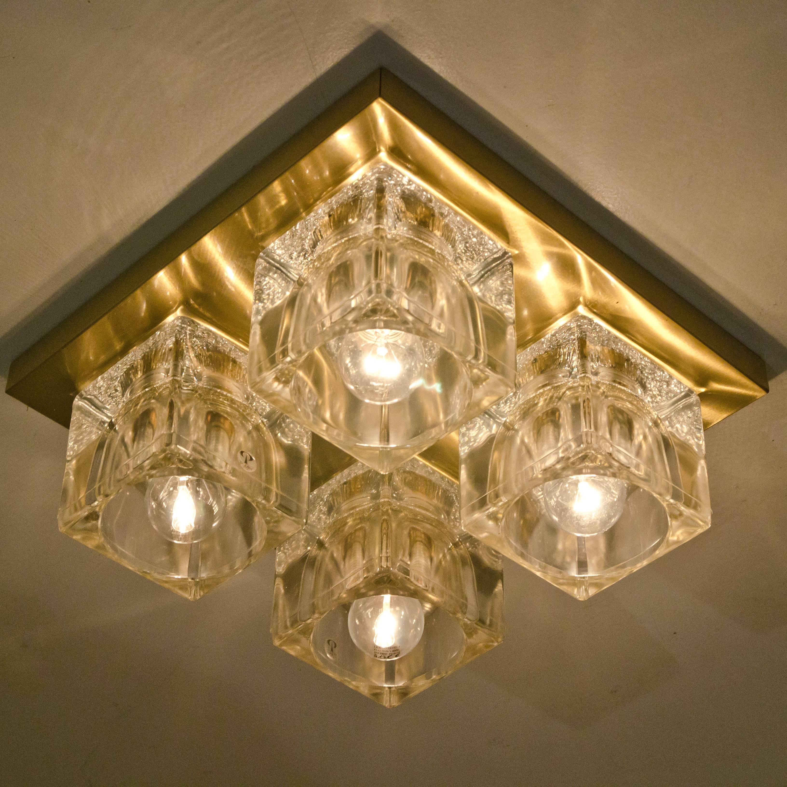 1 of the 4 high-end Peill & Putzler wall/ceiling light fixtures, brass and glass, Germany, 1970. Each sculptural vintage wall light consists of four clear glass cubes on a square brass frame which beautifully reflects the light with a warm