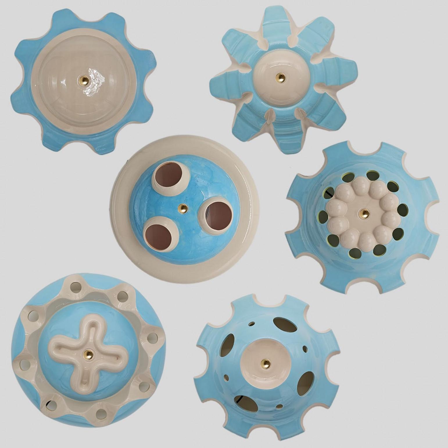 Unique hand-cast ceramic “rosettes” from Jeanine Keizer’s 1990s Lichtpuntje installation are reborn as sculptural pendant lamps. Each set groups five to seven pieces in harmonising colours, creating a gentle, child-friendly glow. The biomorphic