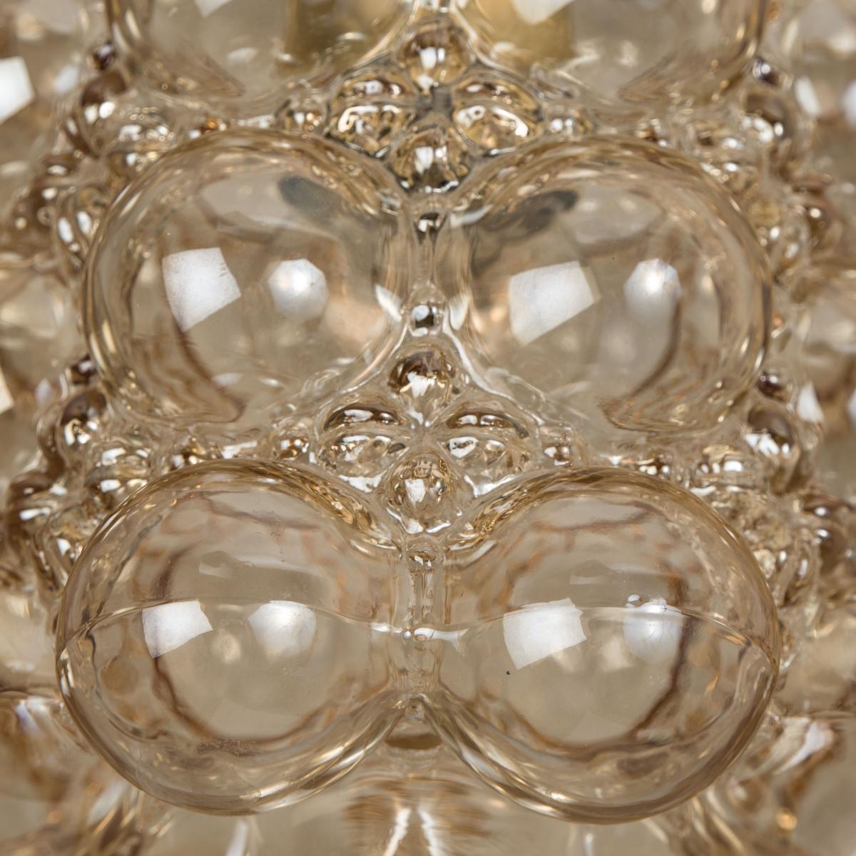 1 des 8 magnifiques lustres ou suspensions en verre bullé conçus par Helena Tynell pour Glashütte Limburg. Un classique du design, le verre soufflé à la main donne une merveilleuse lueur chaude.

Les dimensions : Hauteur 80 cm à partir du plafond,