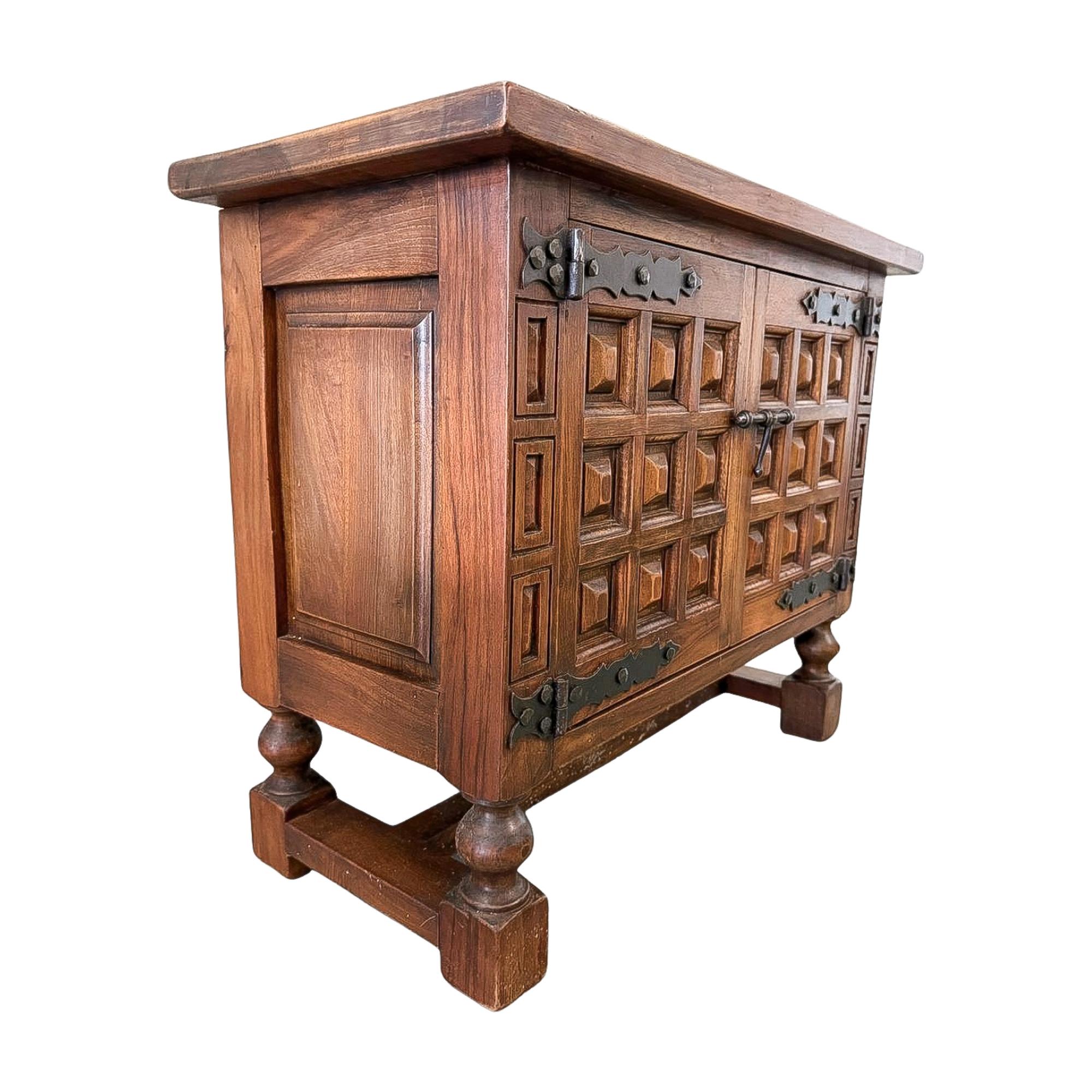 A compact Renaissance Revival sideboard cabinet in walnut, late 19th century. The design showcases deep geometric paneling across the doors and drawers, iron strap hinges, and a thick overhanging top. Raised on shaped bracket feet with a stepped