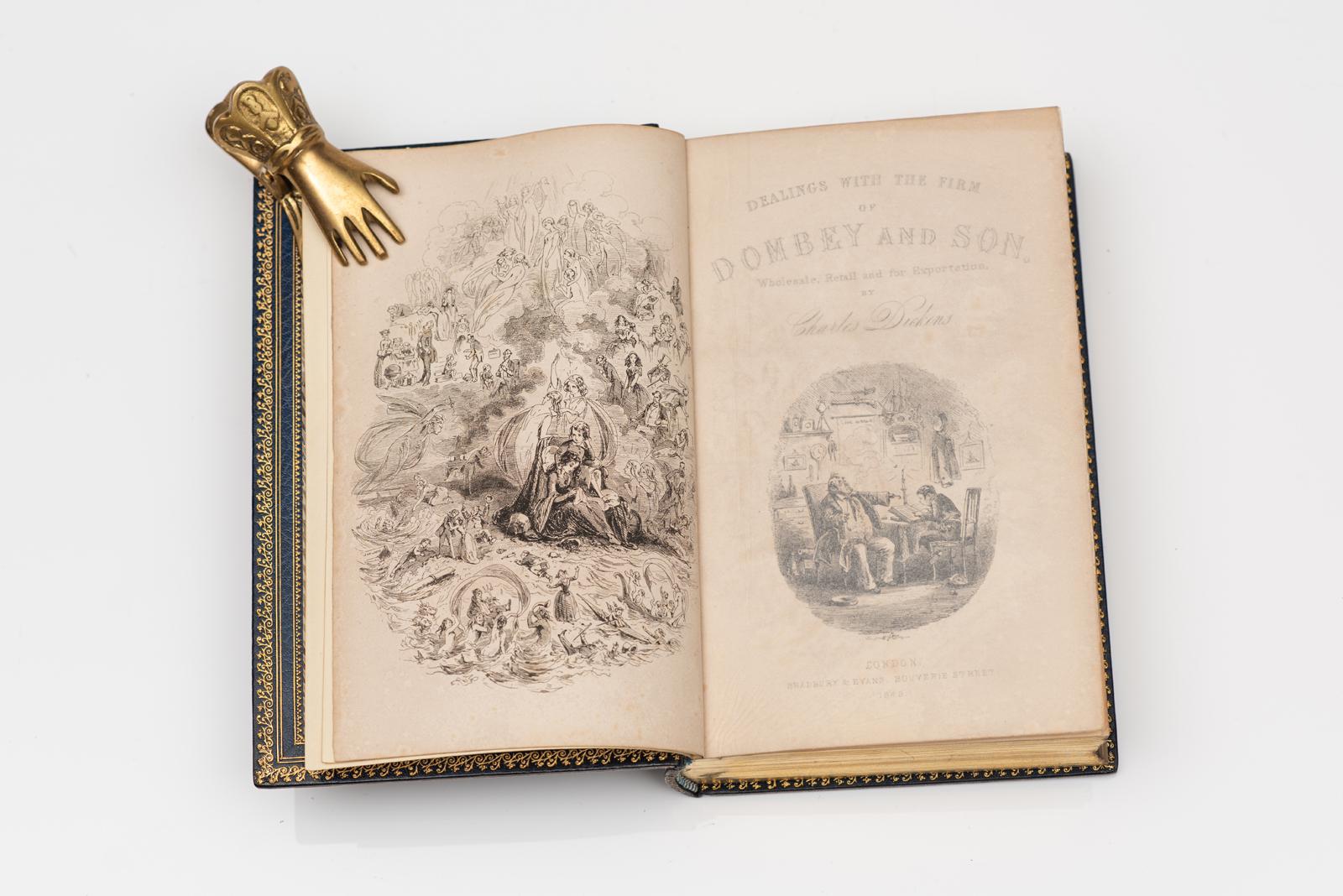 1 Vol. Charles Dickens, Dombey e hijo. Ilustrado por H.K. Browne. Primera edición. Dedicado a la marquesa de Normandía. Cubiertas de cuero marroquí azul. Retrato dorado de Charles Dickens en la portada. Firma dorada de Charles Dickens en la