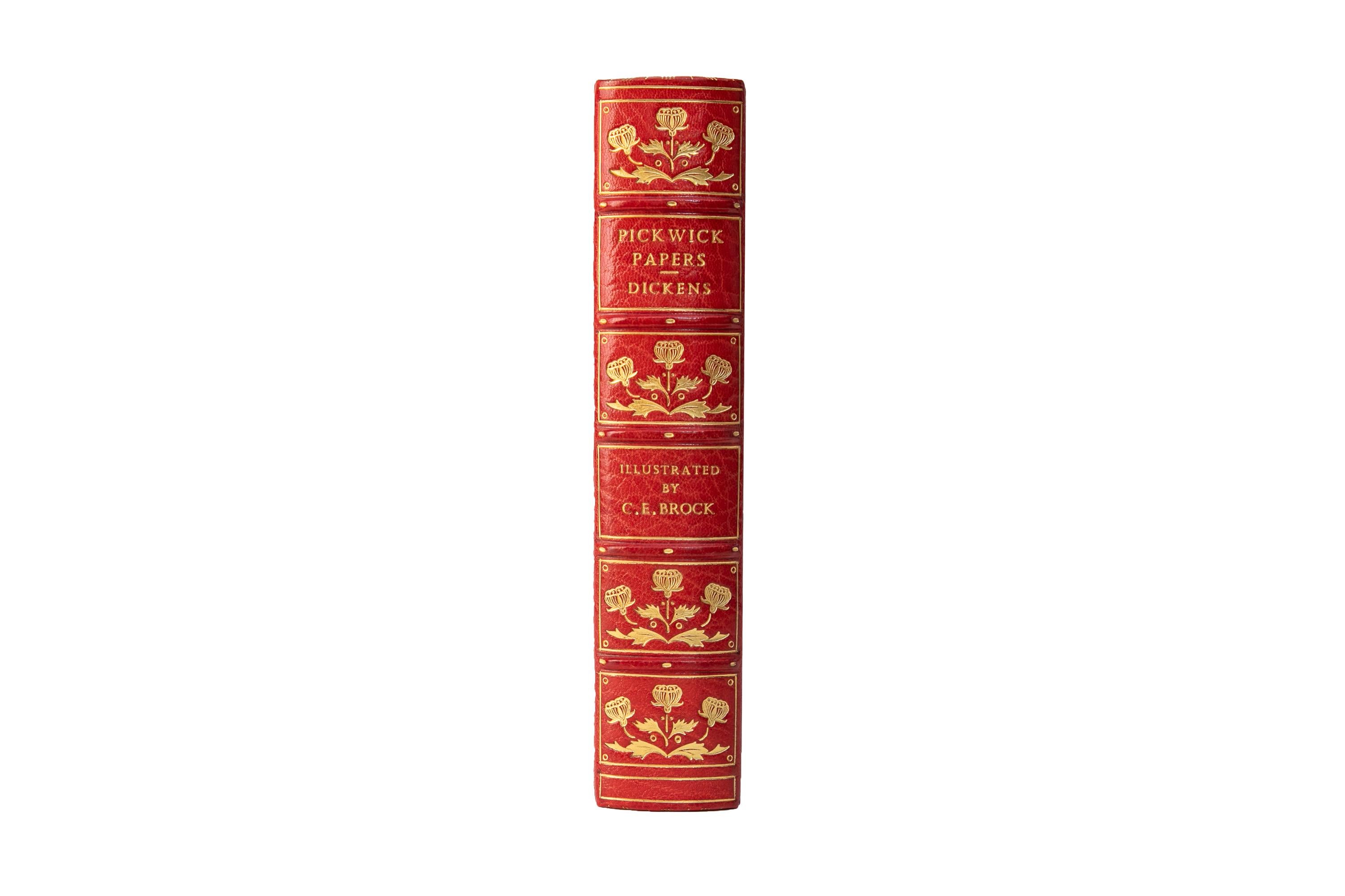 1 Volume. Charles Dickens, The Pickwick Papers. First Brock Edition. Bound by Bayntun in full red morocco with the covers displaying a multi-color inlay scene with 3 figures bordered in gilt-tooling. The Raised band spine displays gilt-tooled