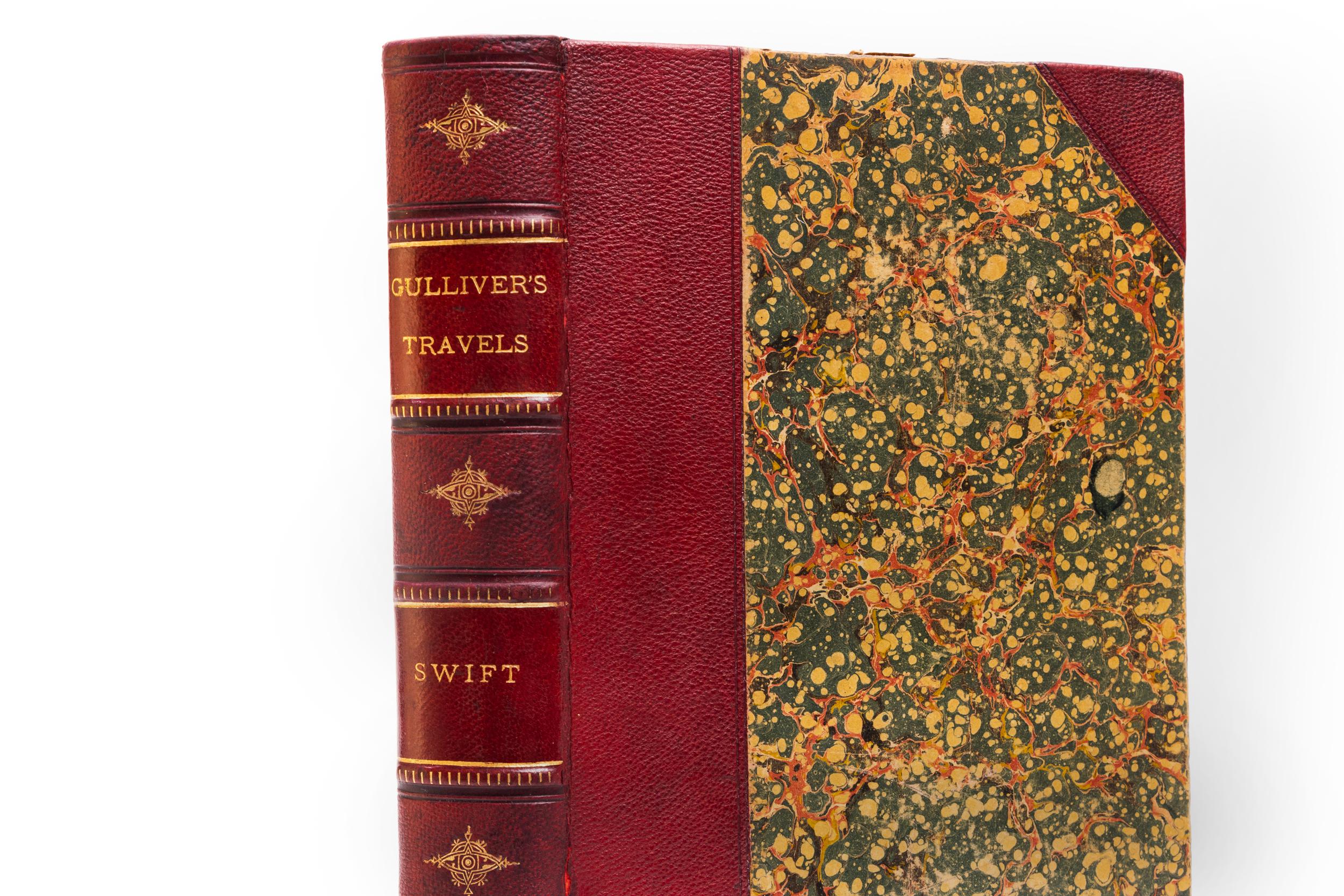1 Volume. Jonathan Swift, D.D. Gulliver's Travels. Bound in 3/4 red morocco. Marbled boards. Raised bands. Decorative gilt emblems on spines. All edges marbled. Marbled endpapers. Illustrated. Embellished with numerous wood-engravings. Published: