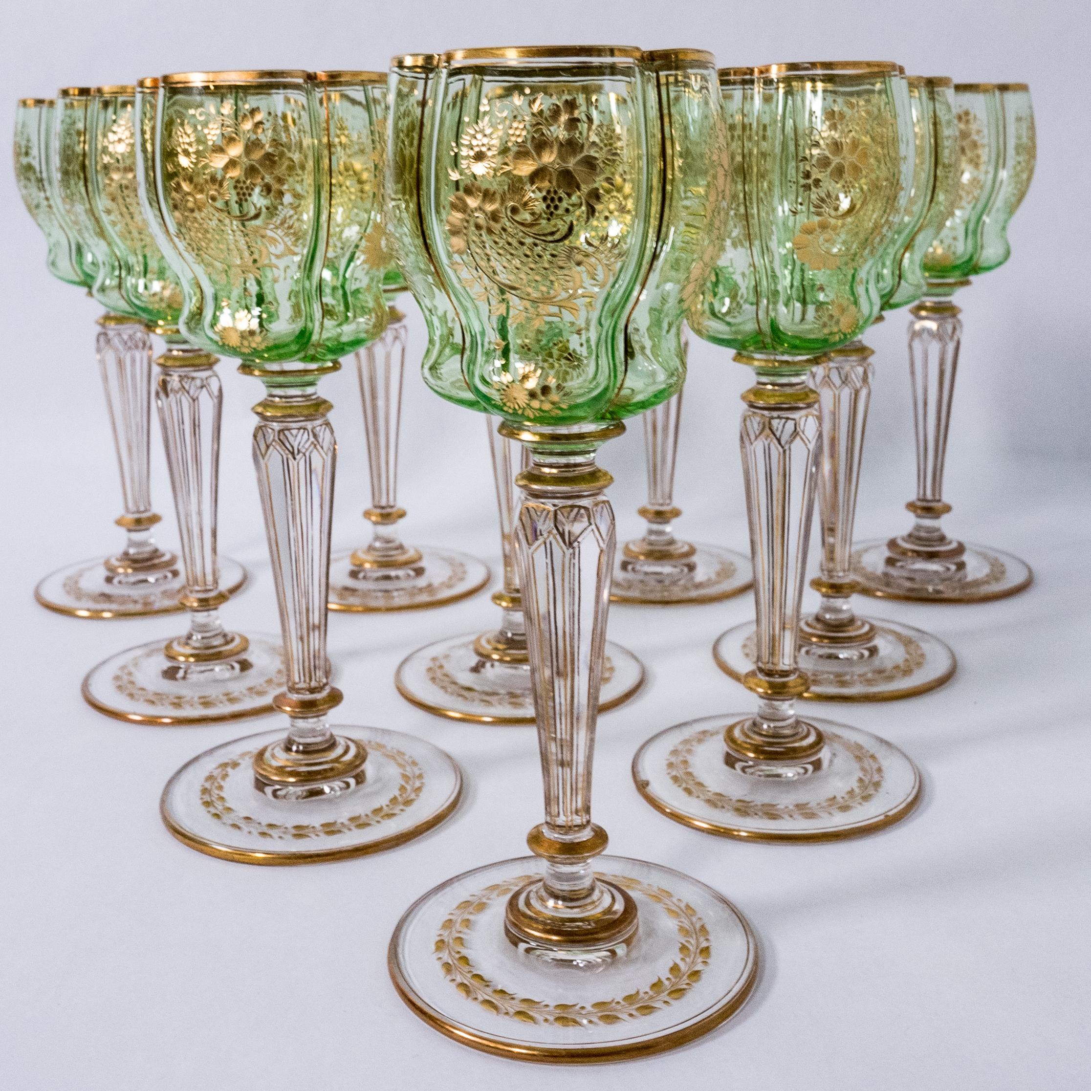 An exquisitely crafted set of white wine glasses by the storied Gilded Age firm of Moser. This group of 10 has an unique quatre foil shaped top with a triple stepped stem and fully wheel cut bowl and base. The shade of green and the gilding remain