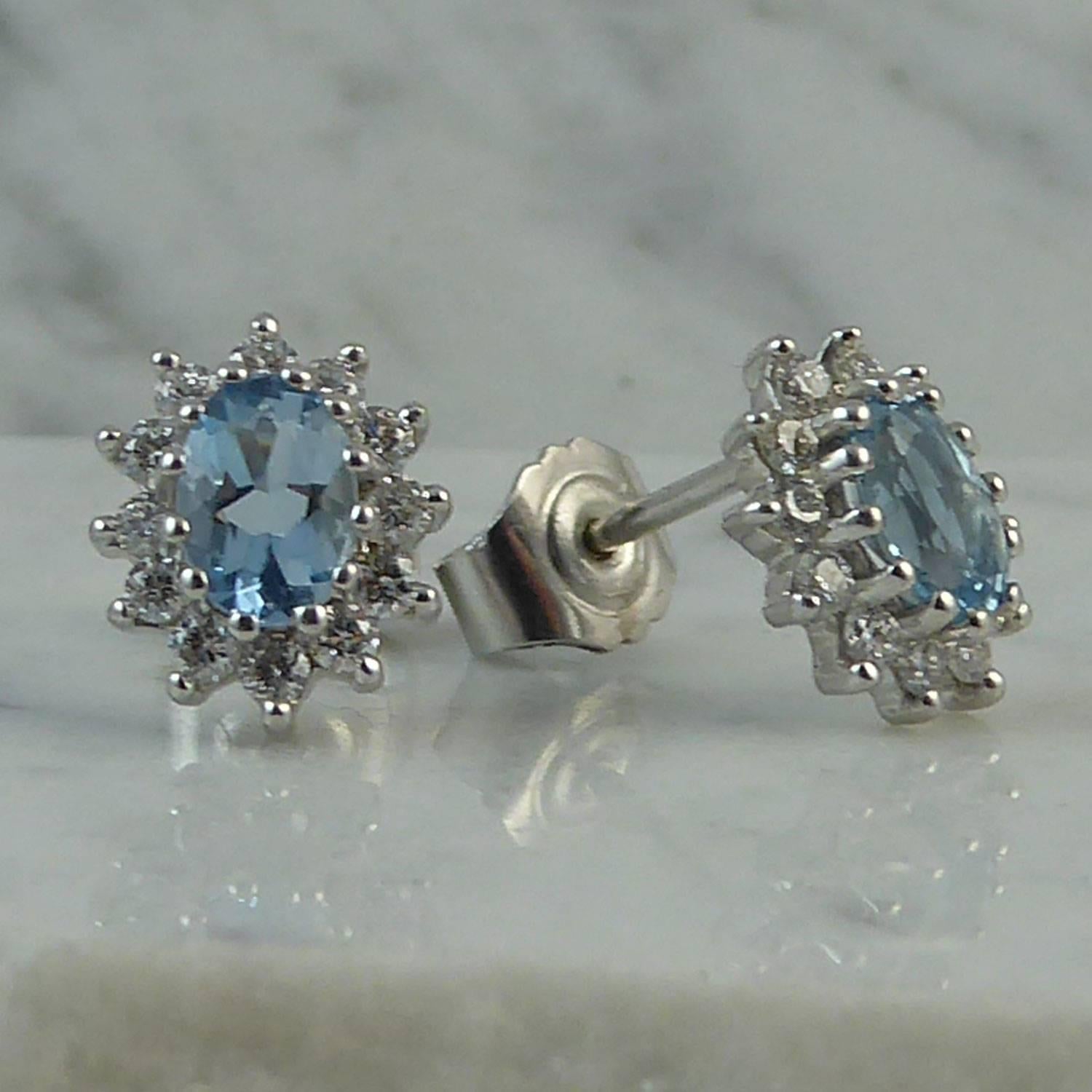 A pair of aquamarine and diamond oval cluster earrings in white gold, set to the centre with an oval mixed cut aquamarine, each measuring approx. 6.0mm x 4.0mm, with a calculated total weight of 1.00ct.  The aquamarines are set to an oval surround