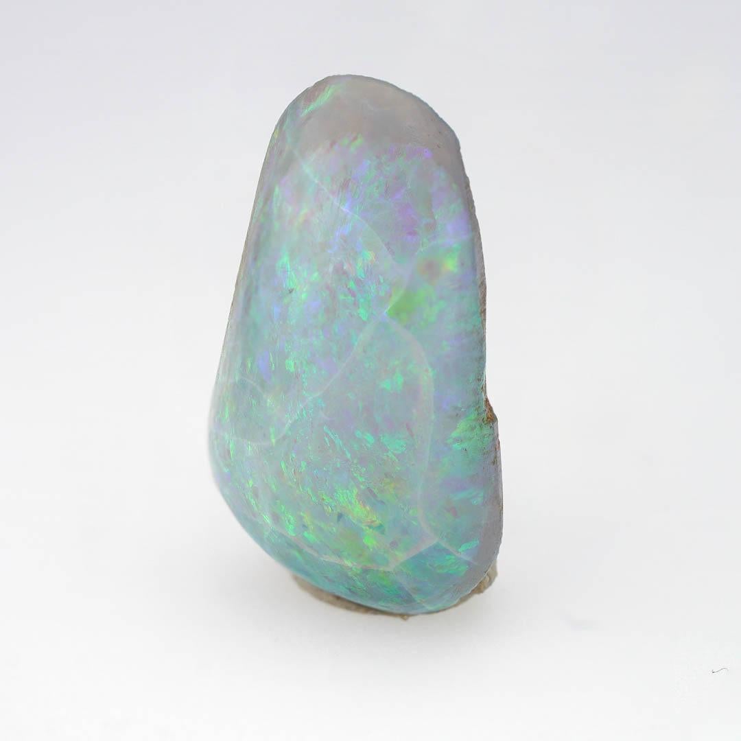 This incandescent 10 ct. Boulder Opal freeform
cabochon features a captivating play of color across its polished surface with electrifying flashes of green, violet, aqua, and gold shimmering through. Mined from the rich opal fields of Australia,