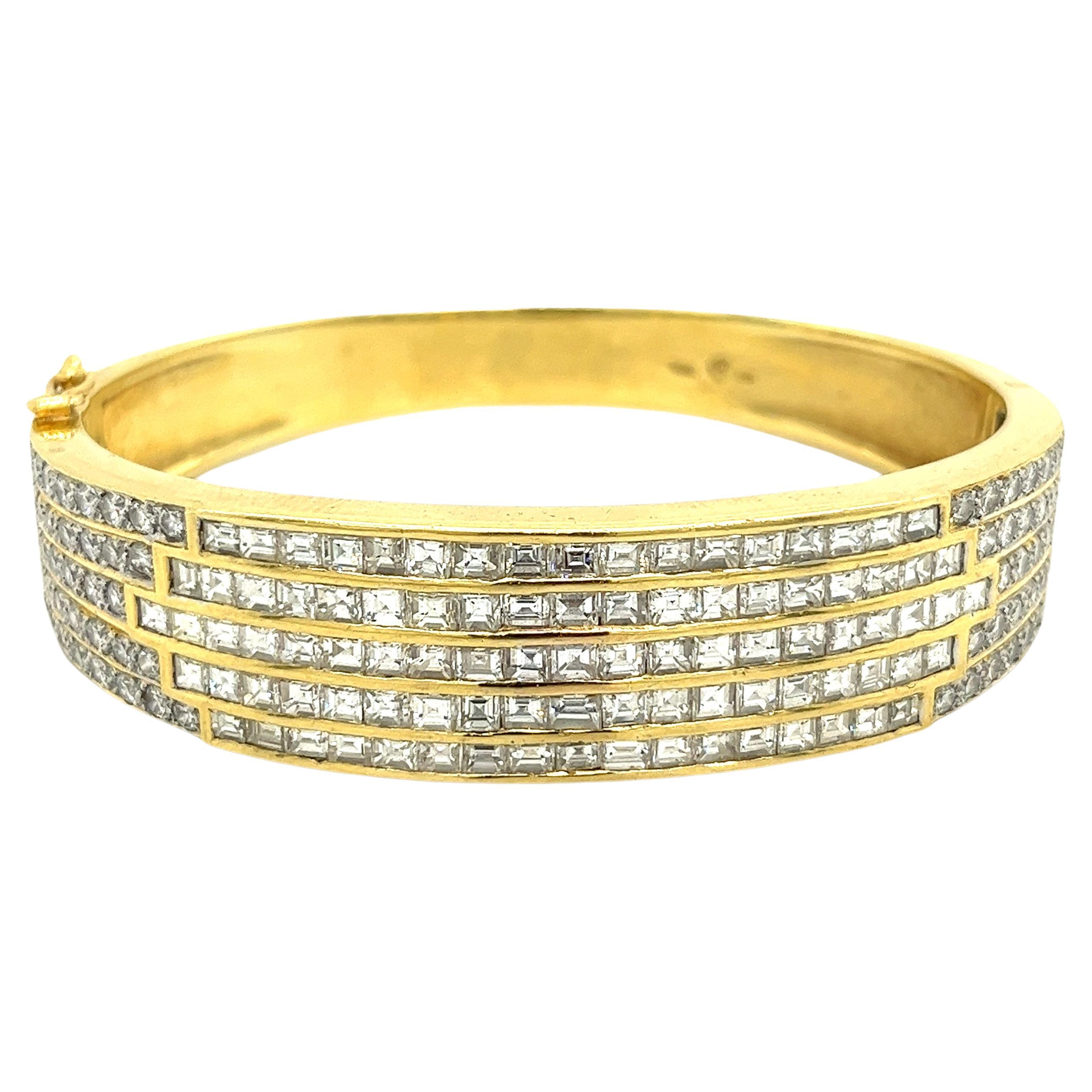 Over 10 carats in natural diamonds, channel and tension set in 18 karat solid yellow gold. Featuring 94 baguette and asscher cut diamonds, flanked by 72 round brilliant cut diamonds. This multi-row cuff bangle bracelet has 5 rows of expertly set